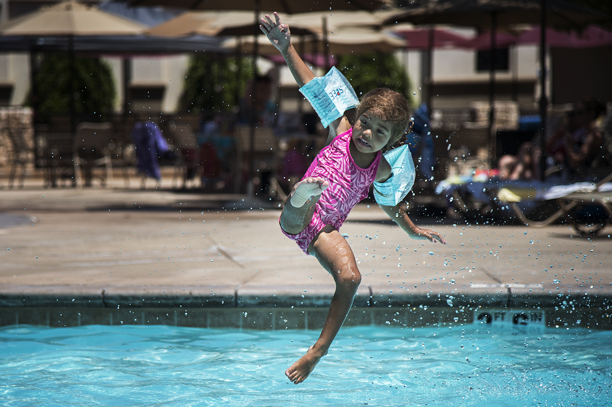 girl with water wings jumping in pool - Documentary Family Photography