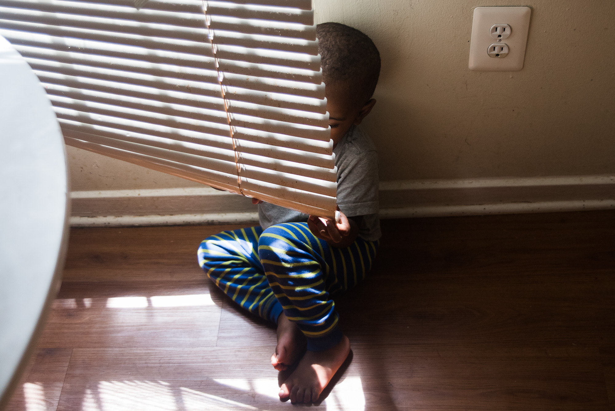 boy hiding behind blinds - Documentary Family Photography