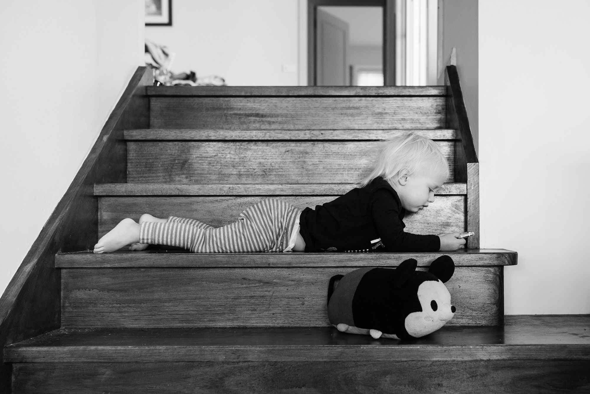 girl lays on stairs with stuffed toy - Documentary Family Photography