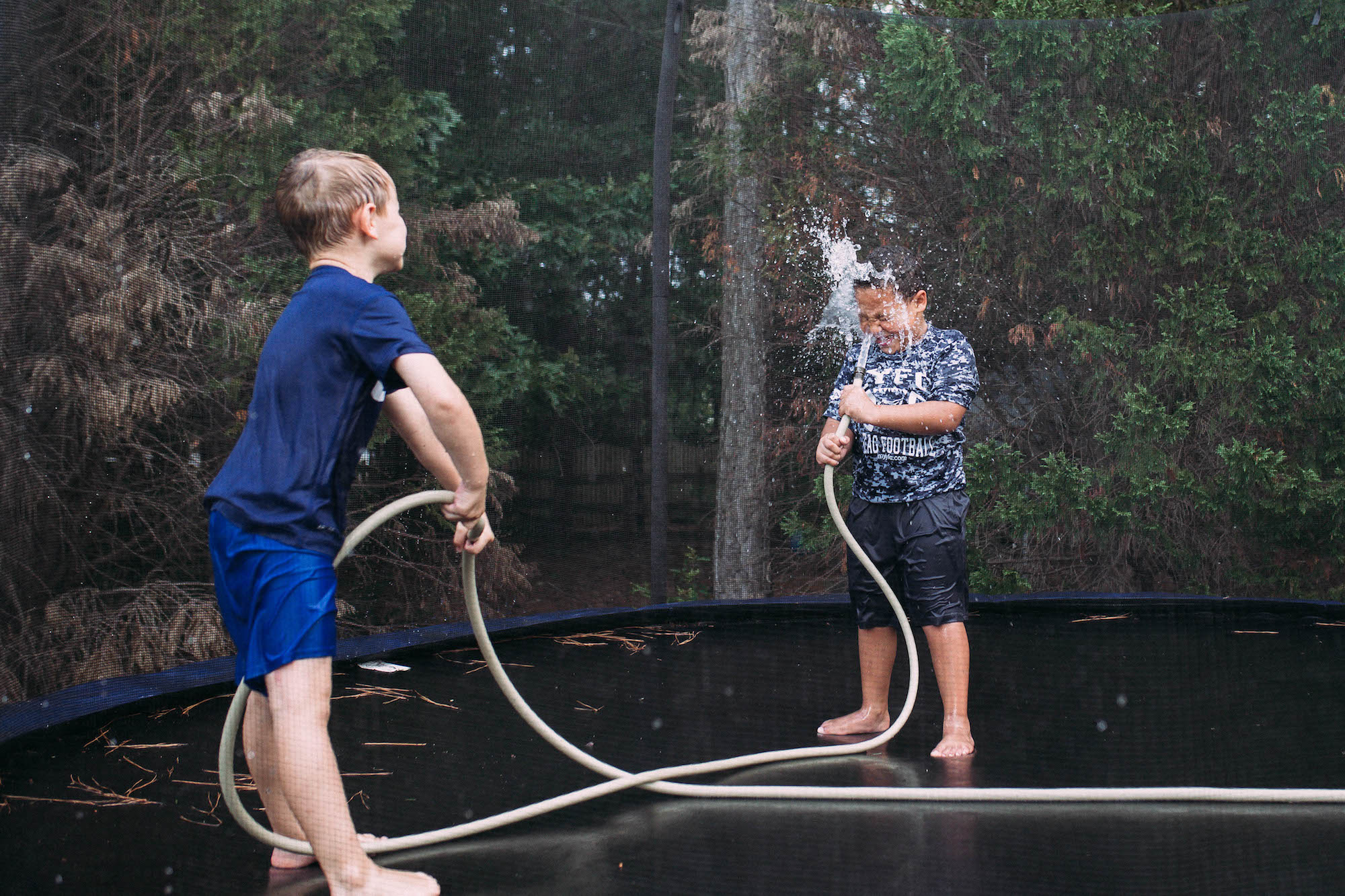 kids with hose on trampoline - Documentary Family Photography