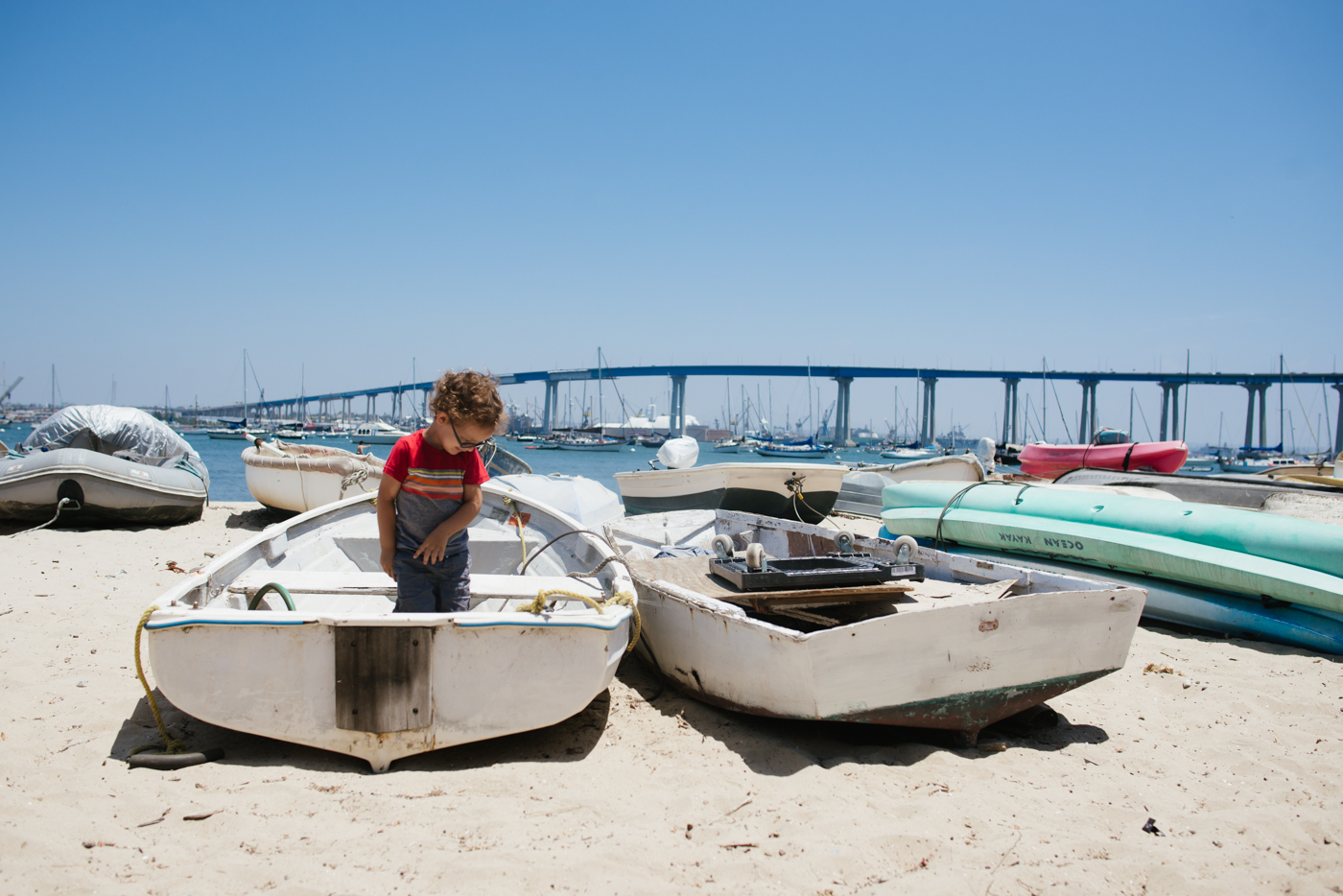 boy in boats on beach - Documentary Family Photography