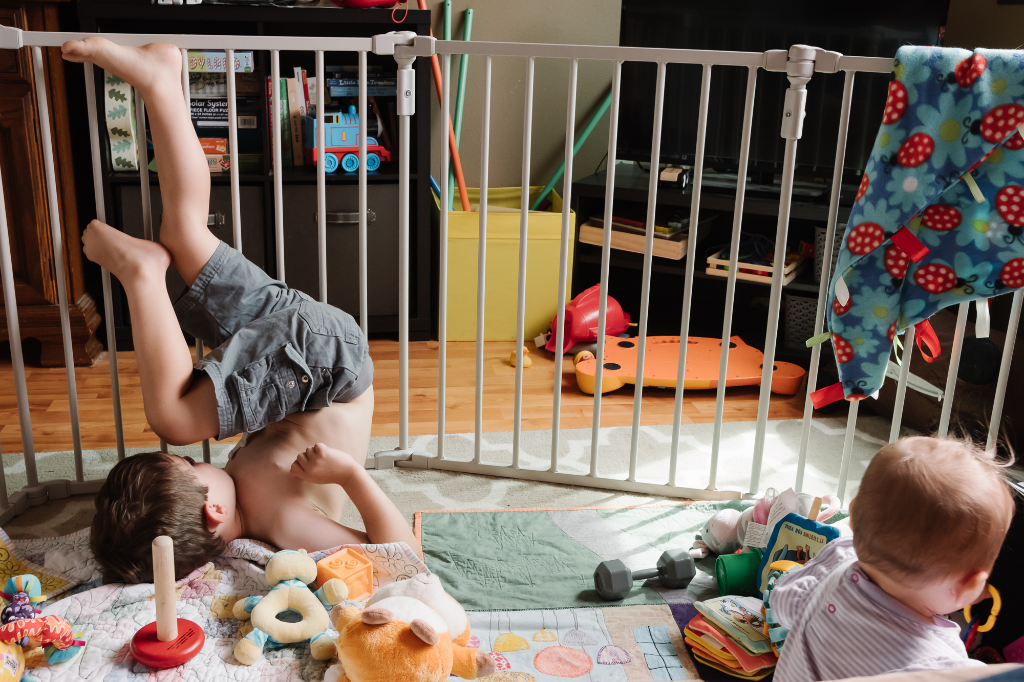 kids play behind baby gate - Documentary Family Photography