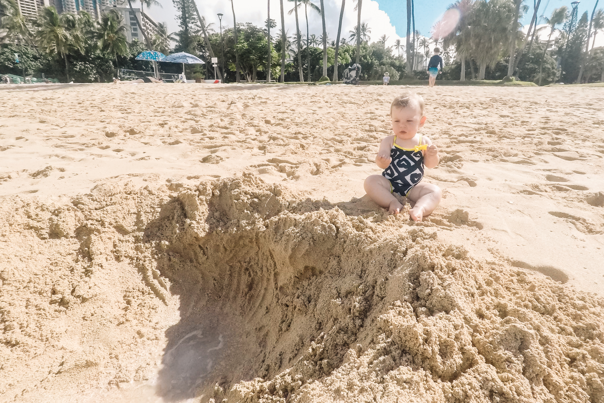 baby looks uncomfortable on beach - documentary family photography