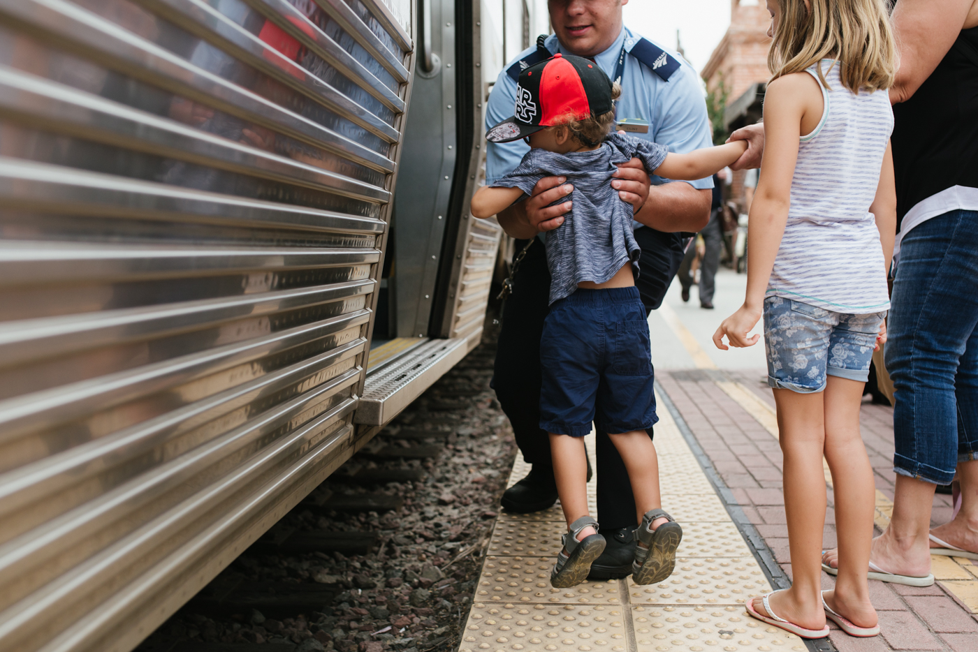 man in uniform picks up child - documentary family photography