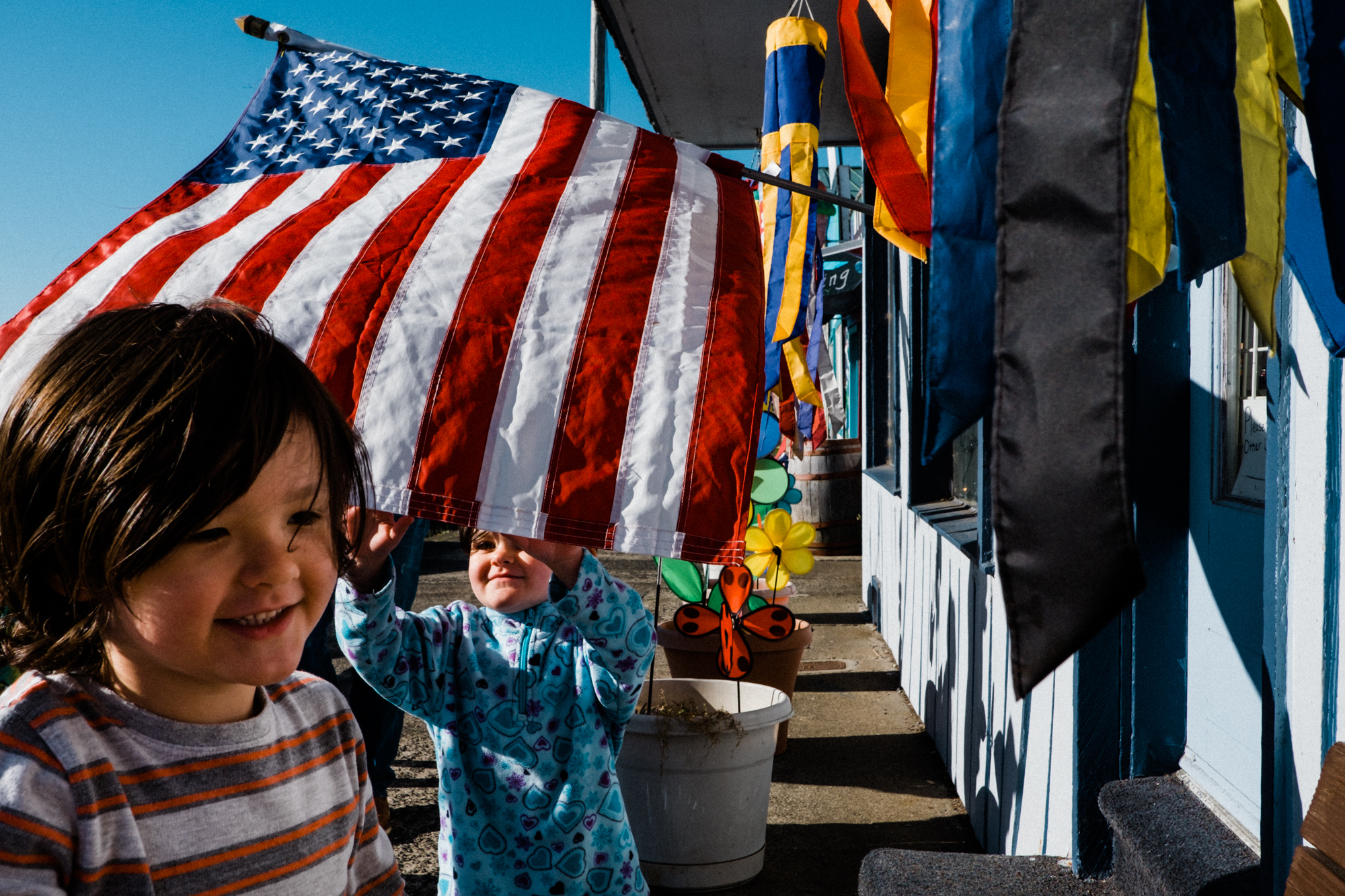 kids play with flag in breeze - Documentary Family Photography