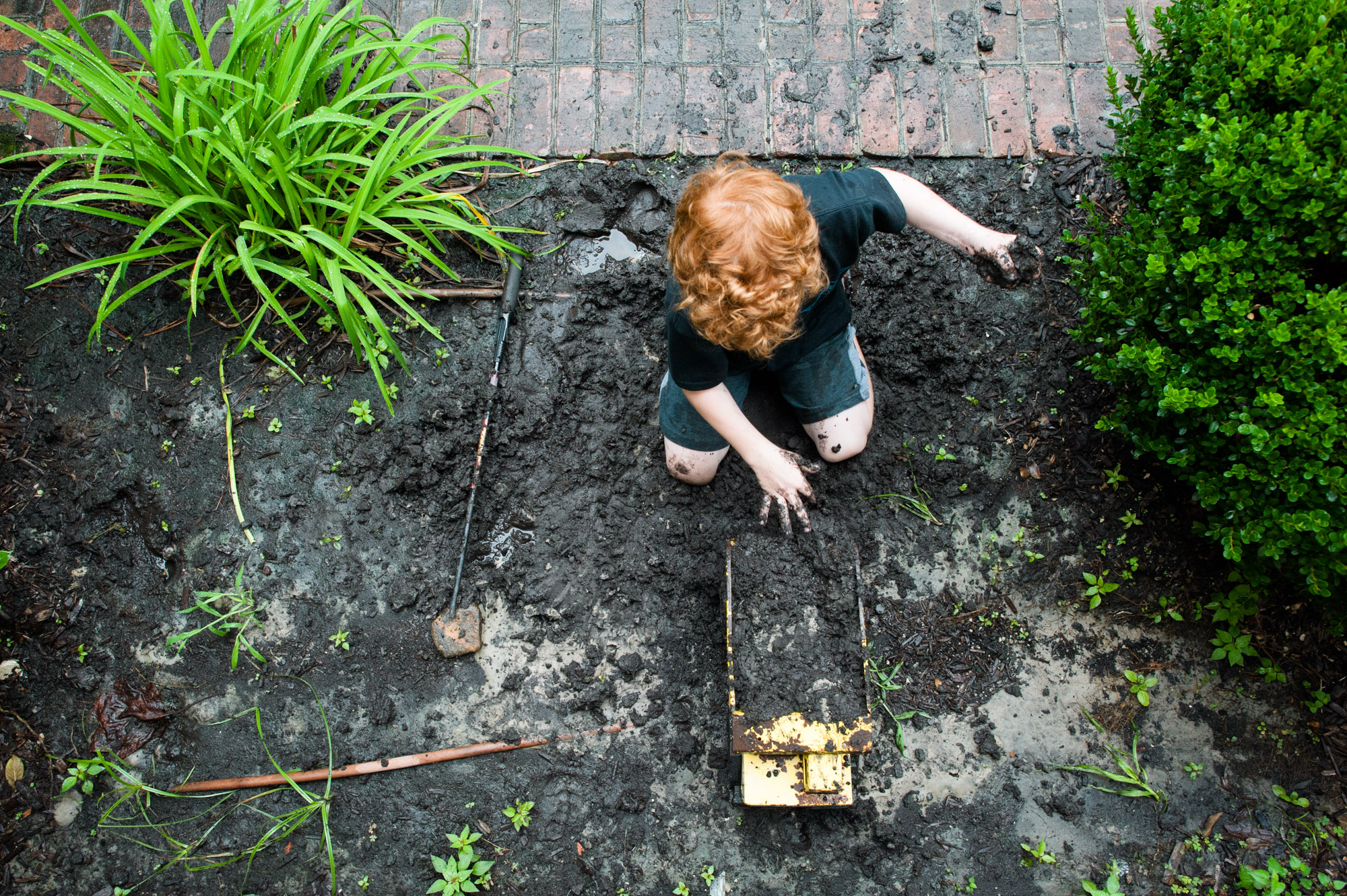 boy plays in garden mud - Documentary Family Photography