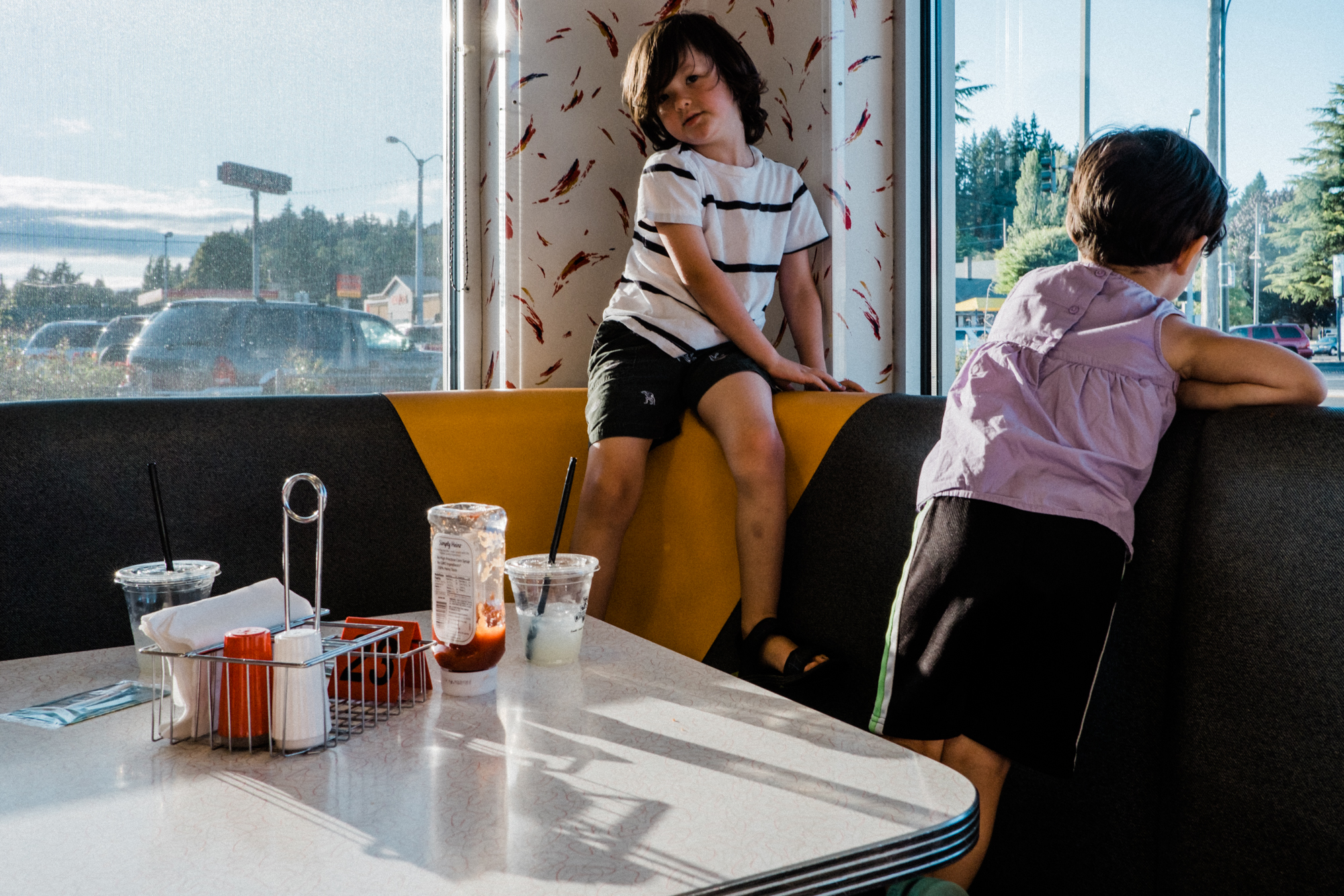 kids climbing on restaurant booth - Documentary Family Photography