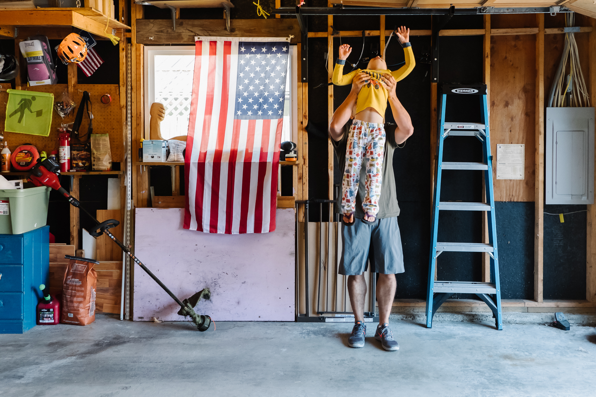 man lifts boy up to pull up bar - Documentary Family Photography