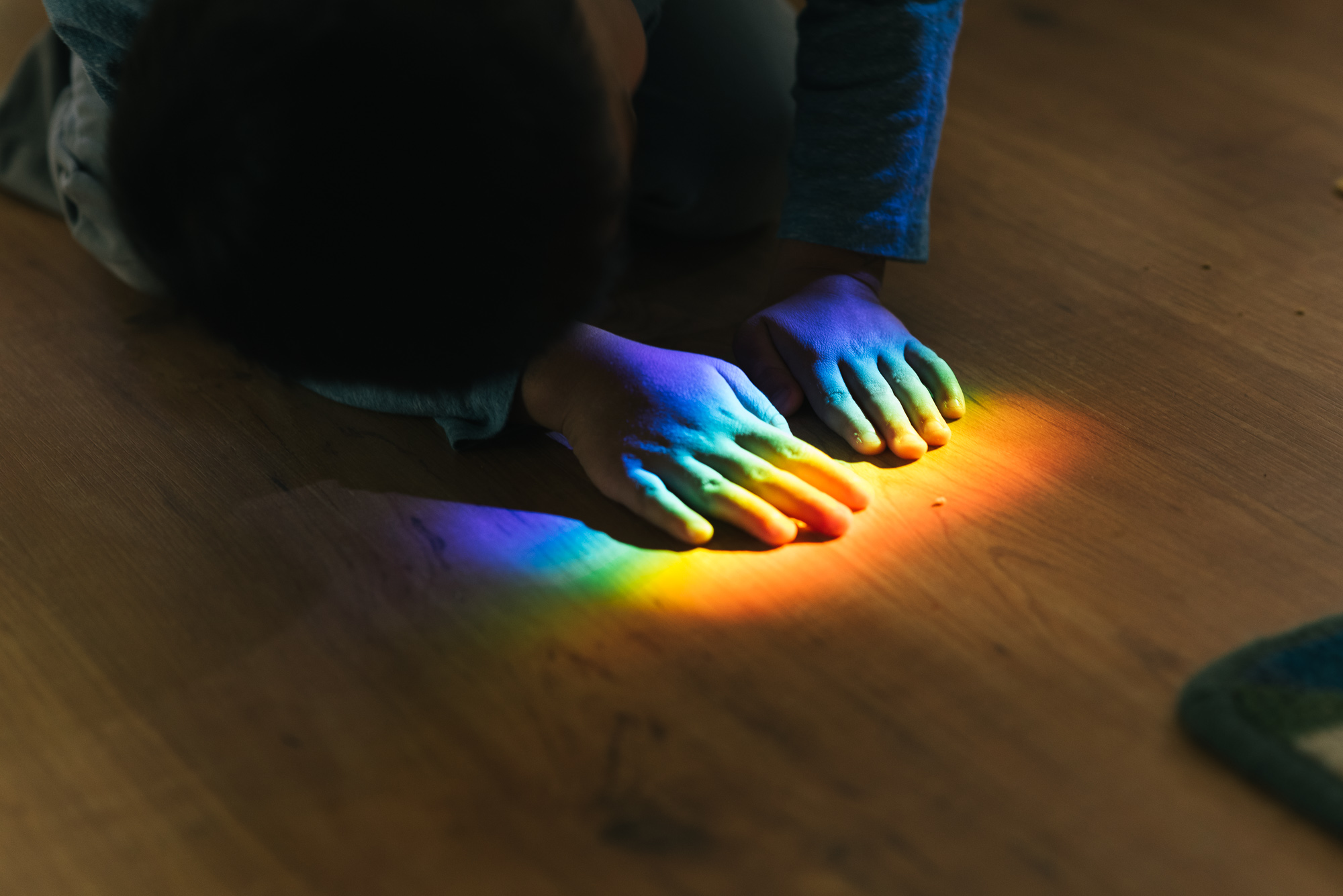 kids hands in rainbow on floor -documentary family photography