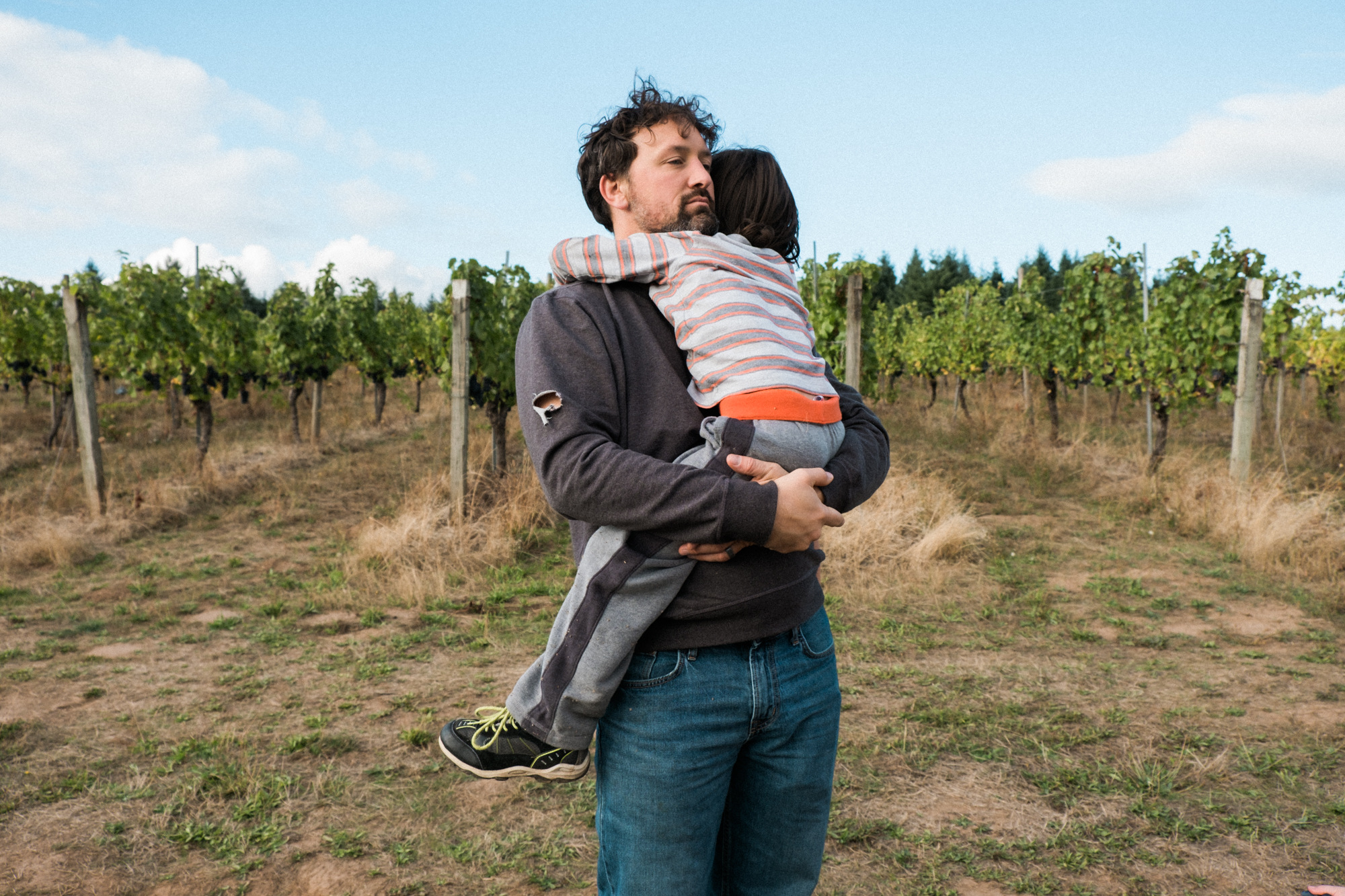 father hugs child field - documentary family photography