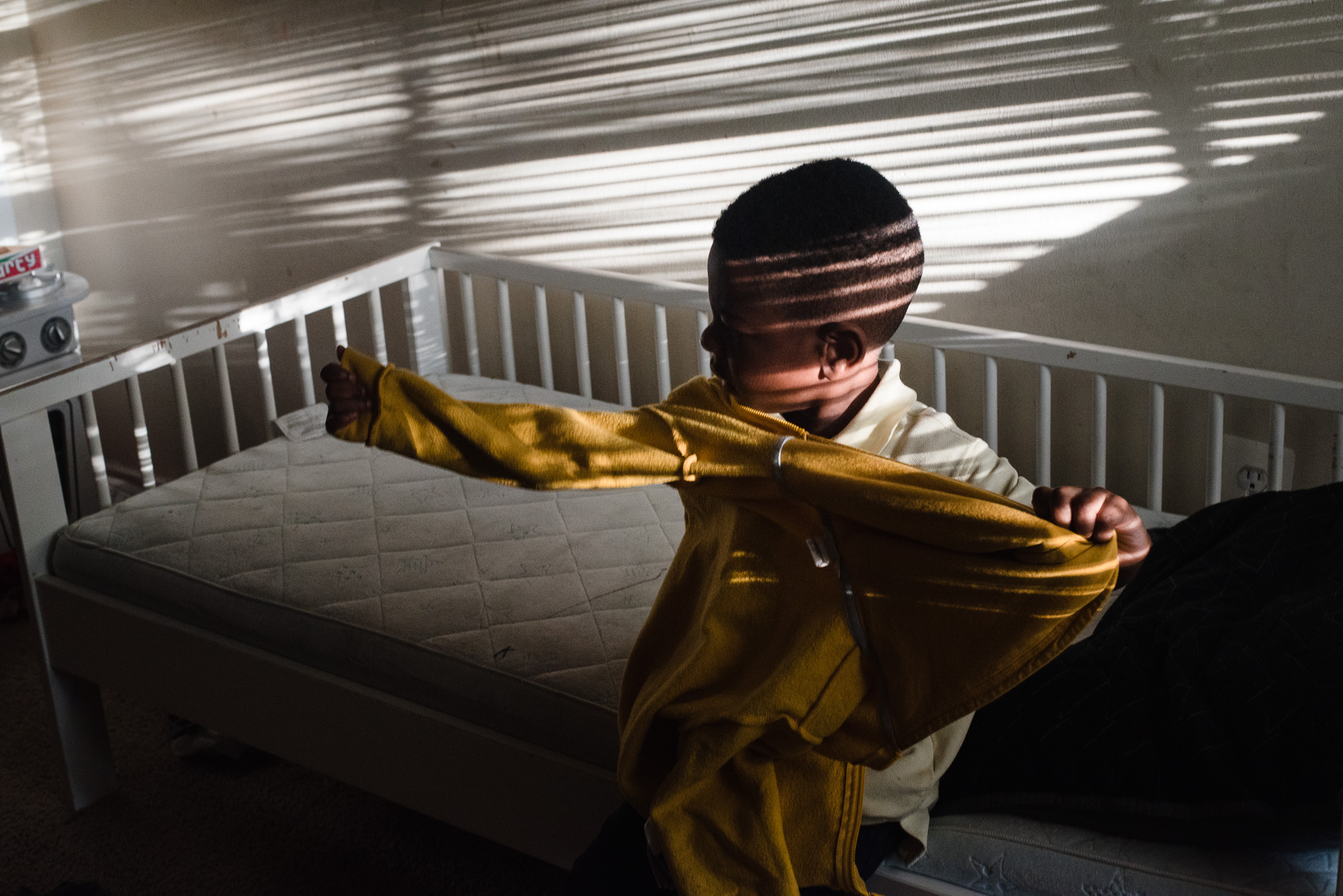 boy in crib with light and shadow - Documentary Family Photography