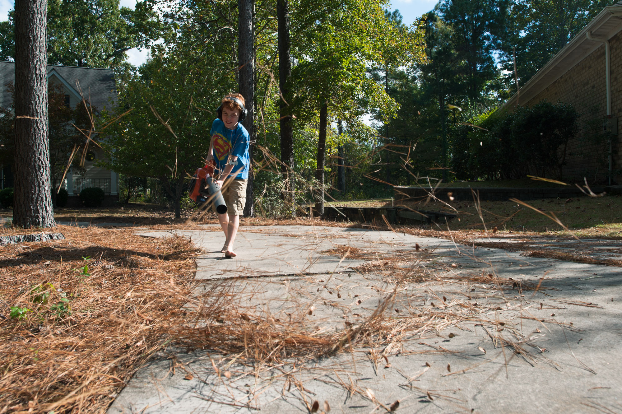 boy blowing debris off sidewalk - documentary family photography