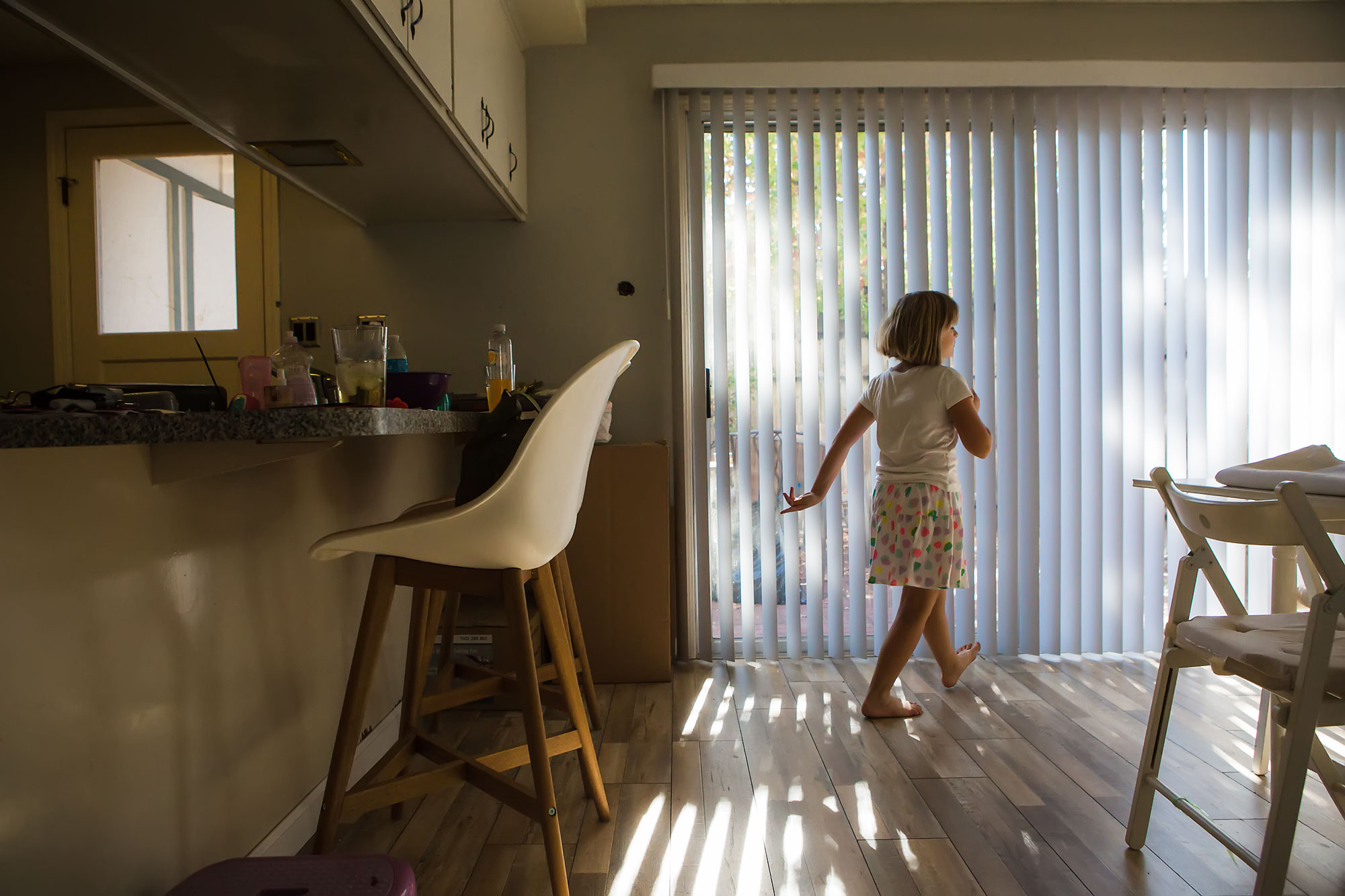 girl walking past sunny window - documentary family photography