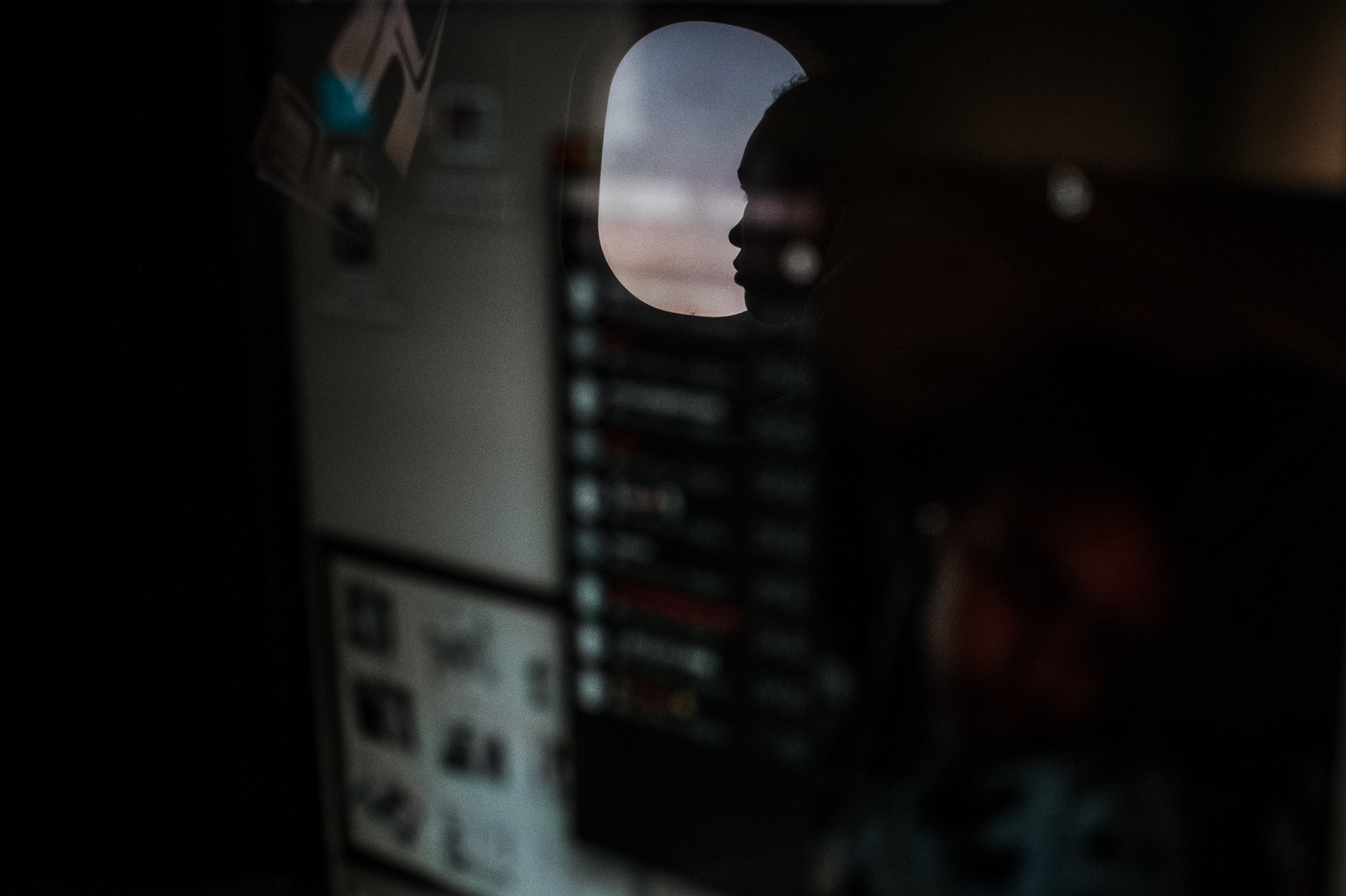 reflection of girls profile in plane window - documentary family photography