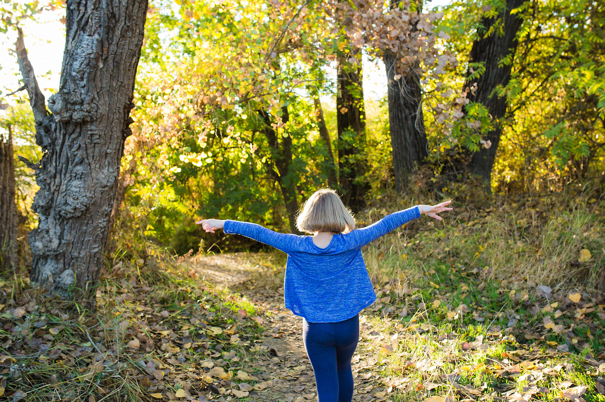 girl with outstretched arms in woods - documentary family photography