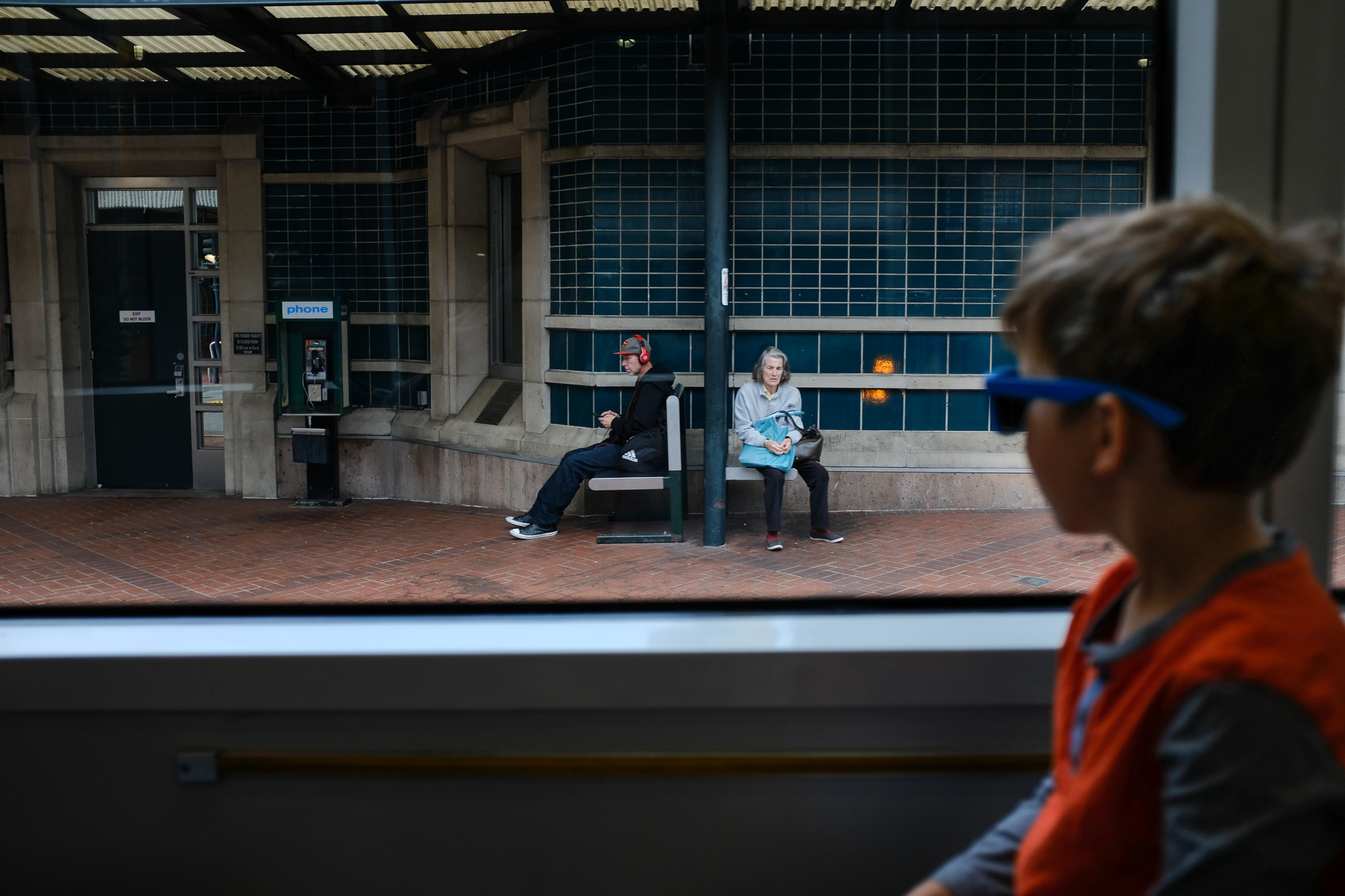 boy looking out window at train platform - documentary family photography