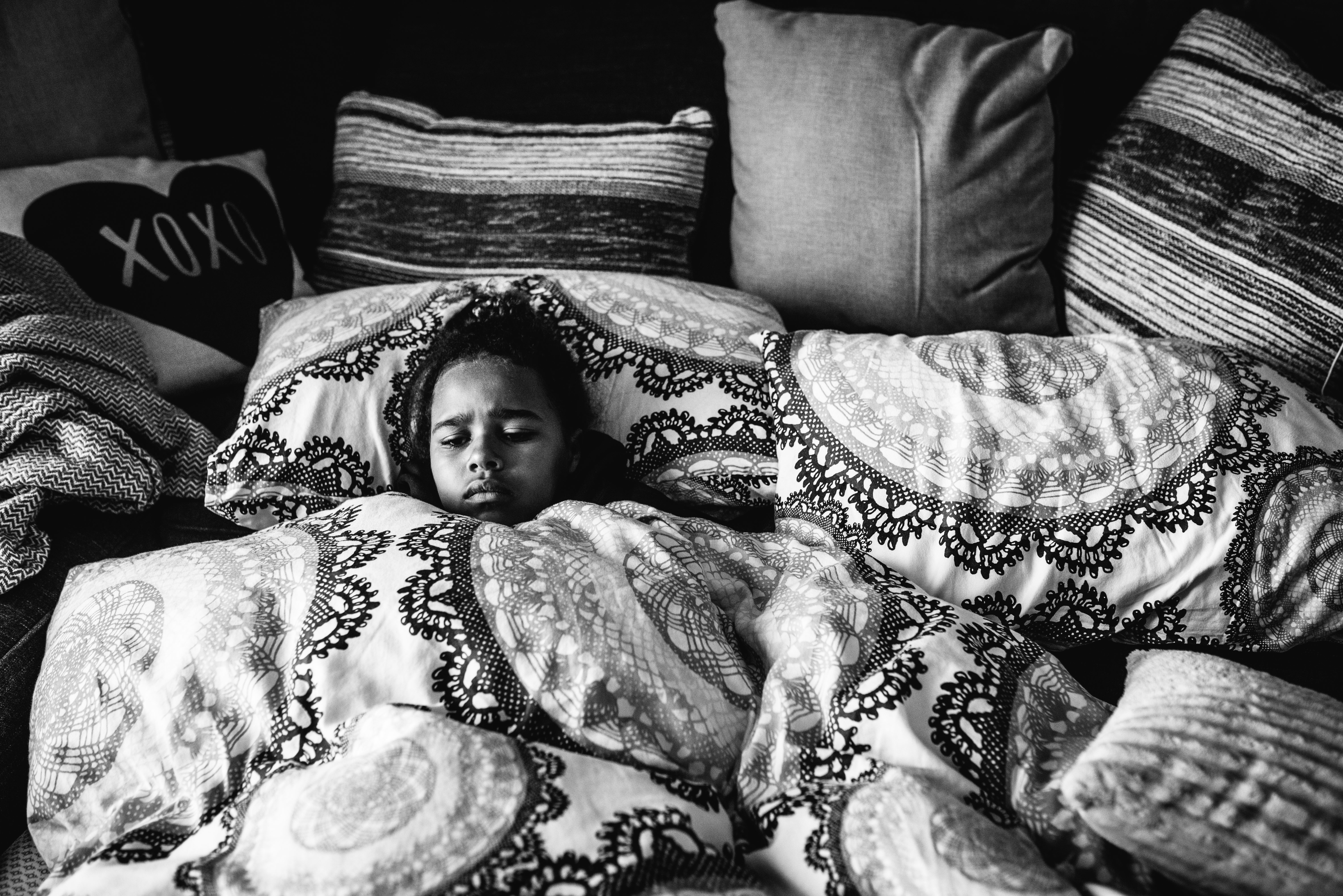 girl snuggled in bedding - documentary family photography