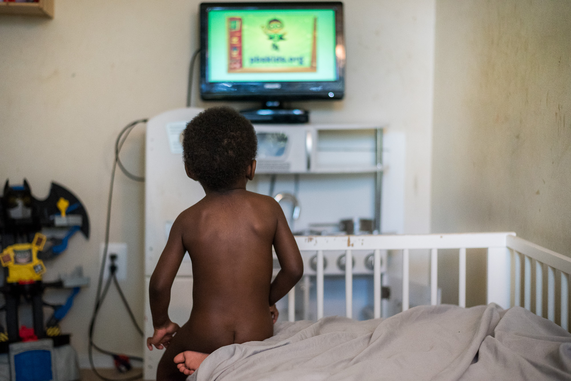 boy watching tv from bed - documentary family photography