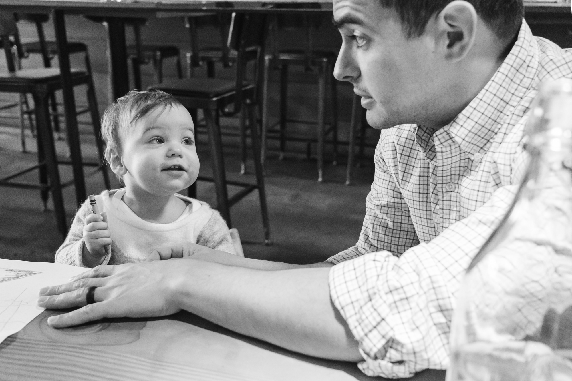 baby makes face at dad while holding crayon - Documentary Family Photography