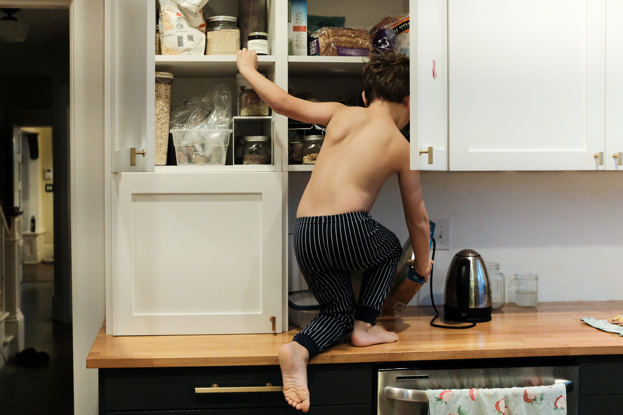 boy climbing in cabinet - Documentary Family Photography