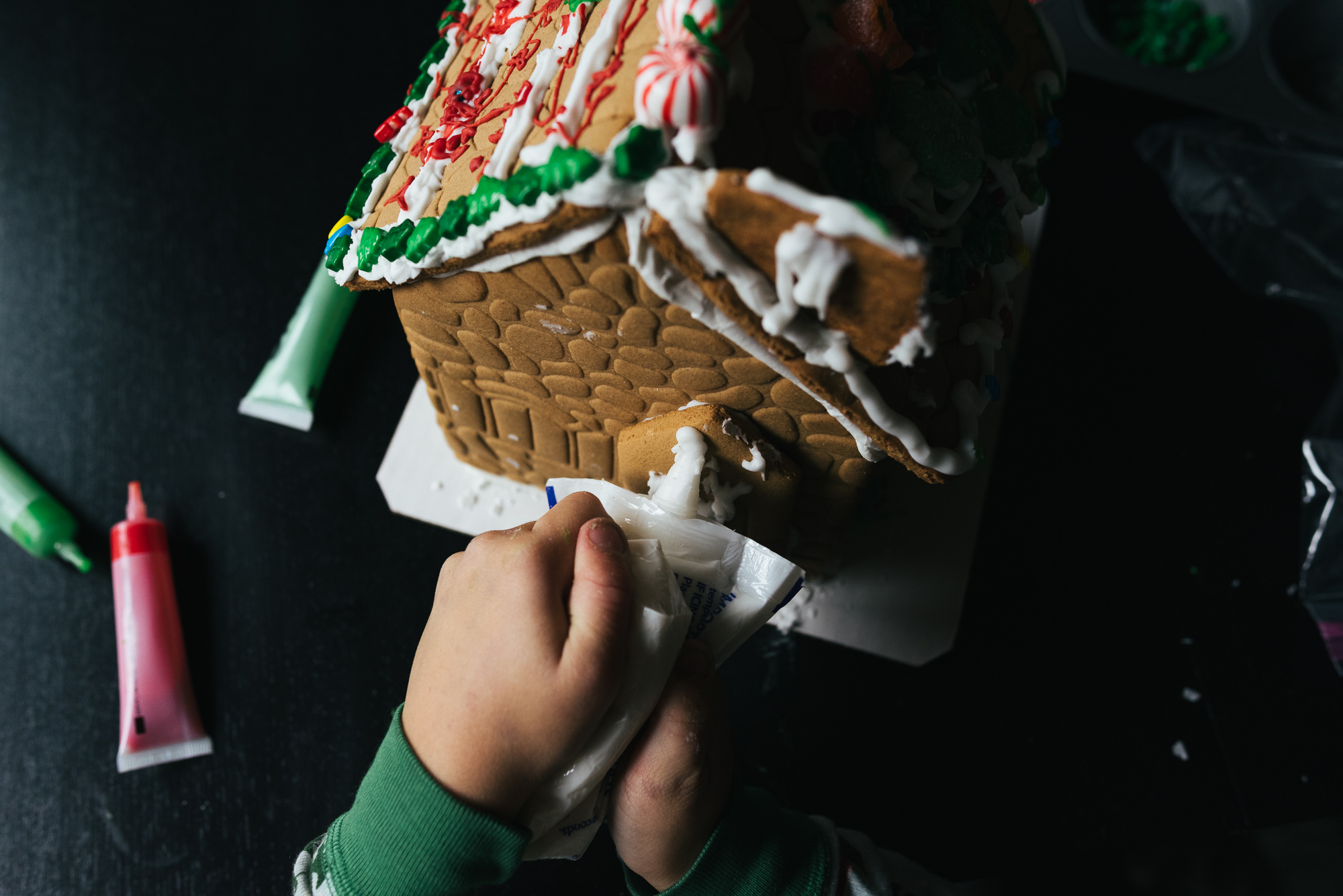 child's hand decorating gingerbread house - Documentary Family Photography