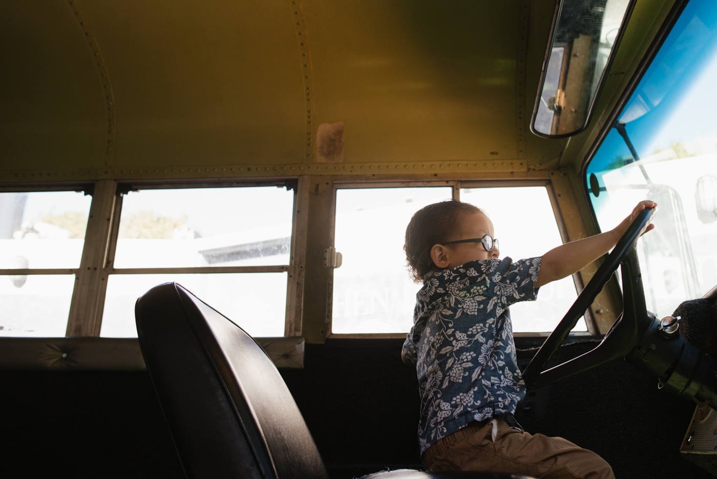 boy pretending to drive bus - Documentary Family Photography