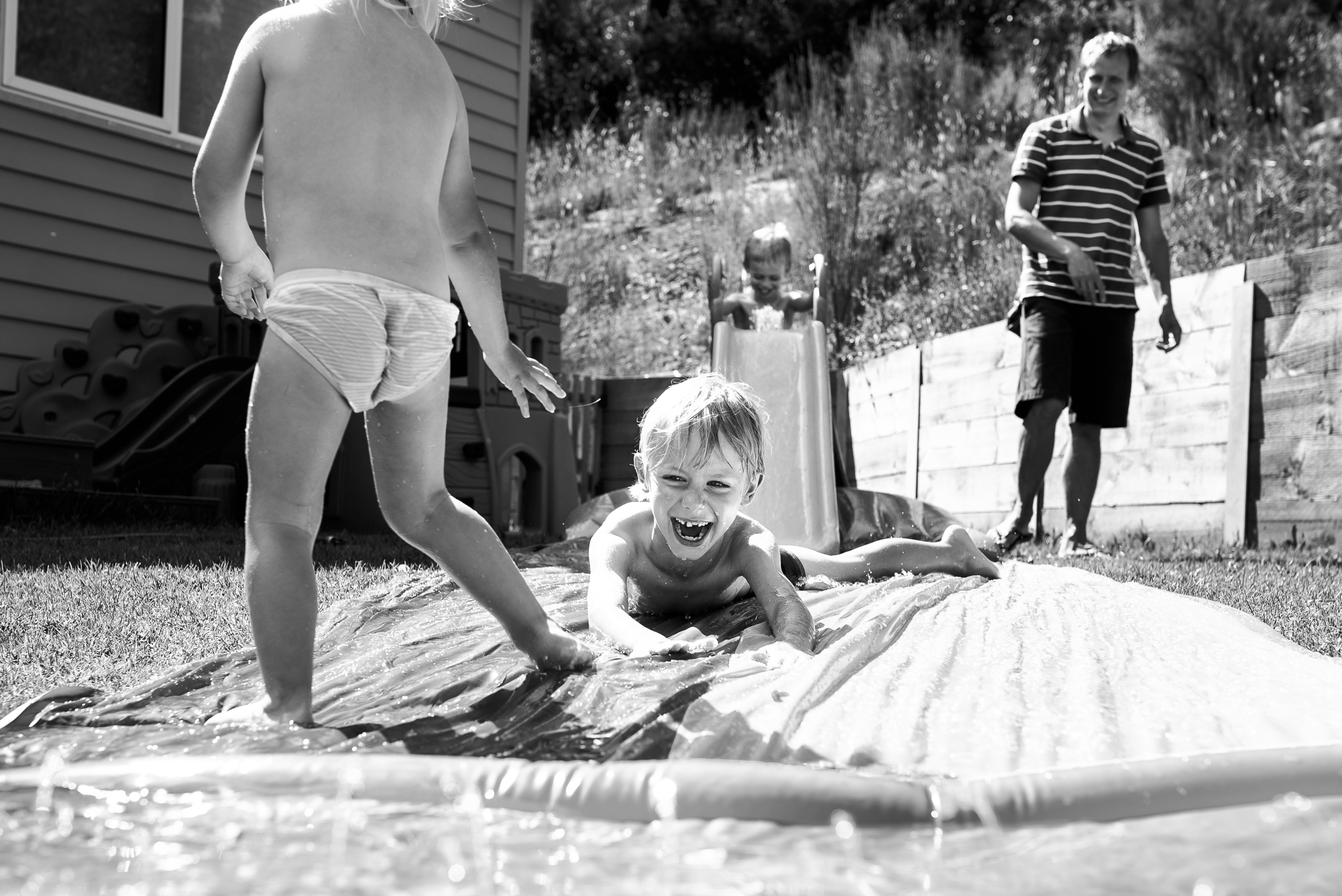 kid on back yard water slide - Documentary Family Photography