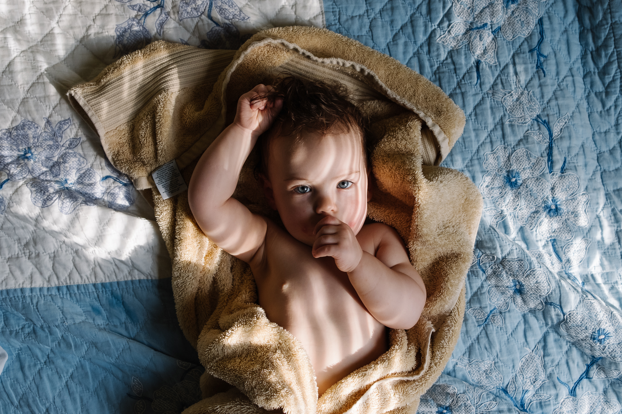 baby in towel on bed - Documentary Family Photography