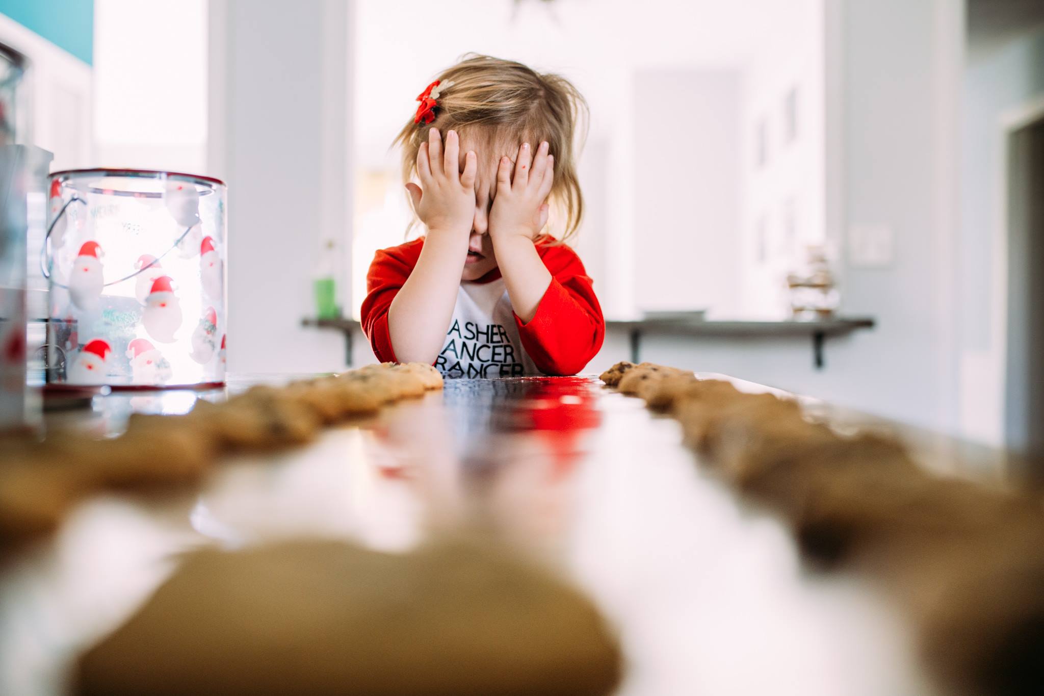 girl hides face with cookies in foreground - Documentary Family Photography