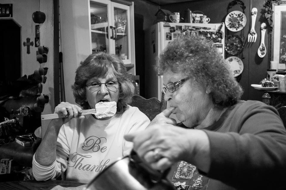 older women licking spatulas while baking - Documentary Family Photography