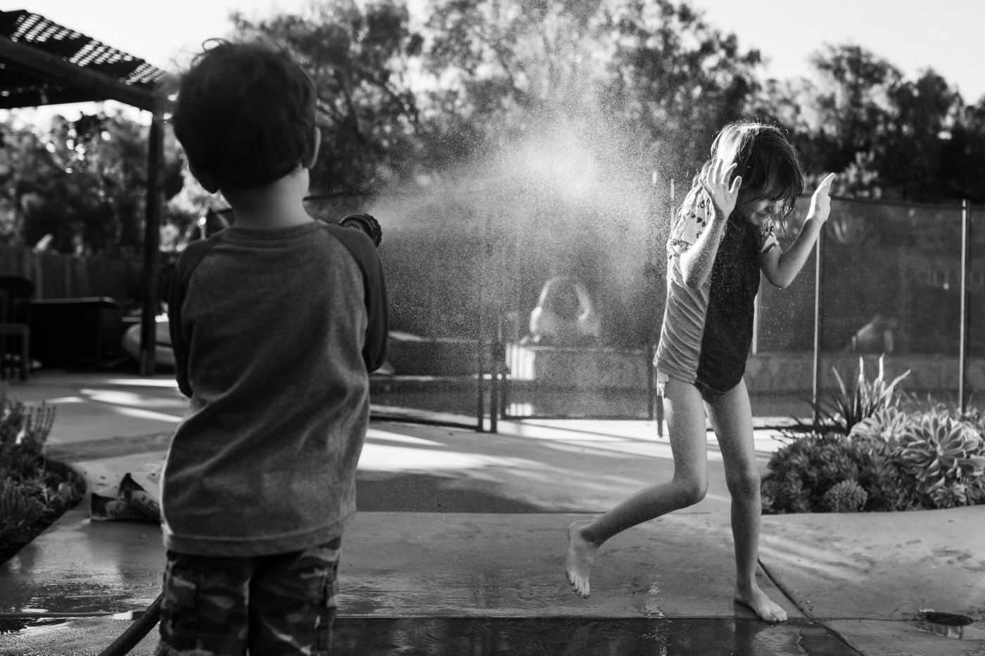 kids spraying each other with hose - documentary family photography