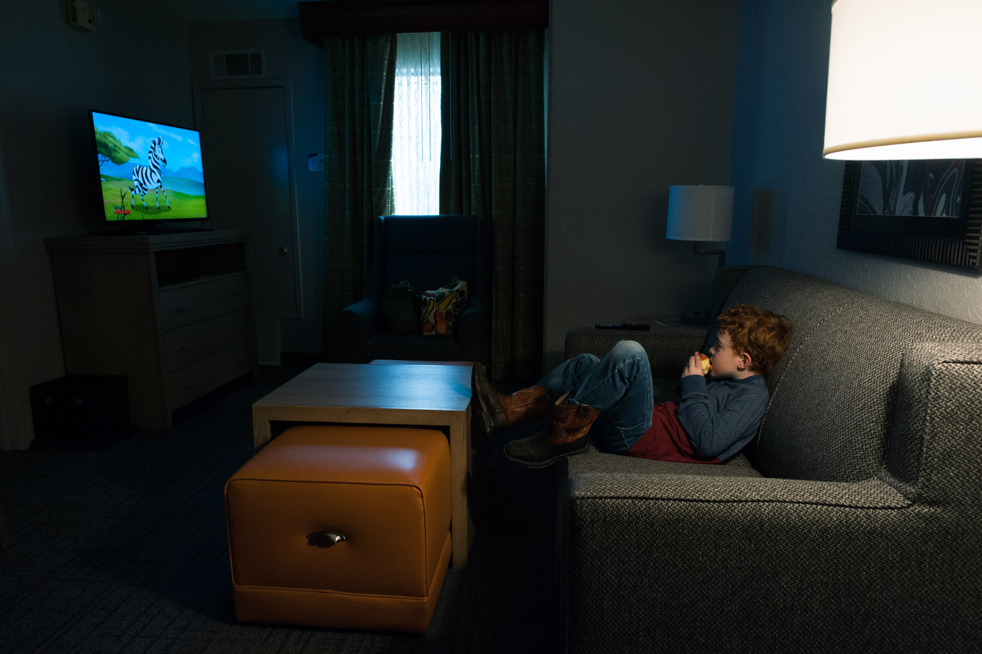 boy watches TV in hotel room - documentary family photography