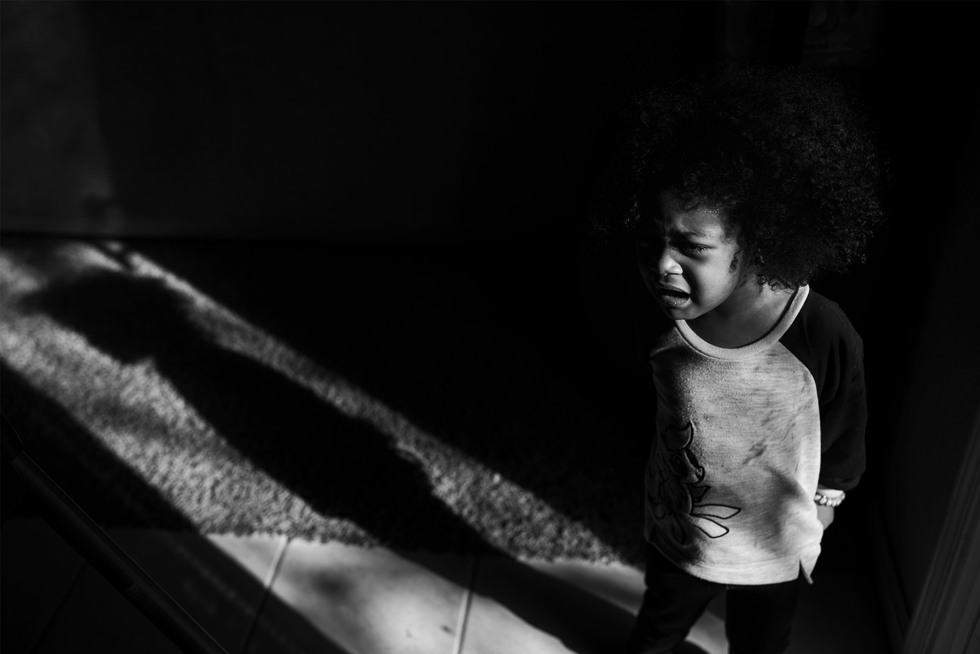 girl yelling in spot of sunlight -documentary family photography
