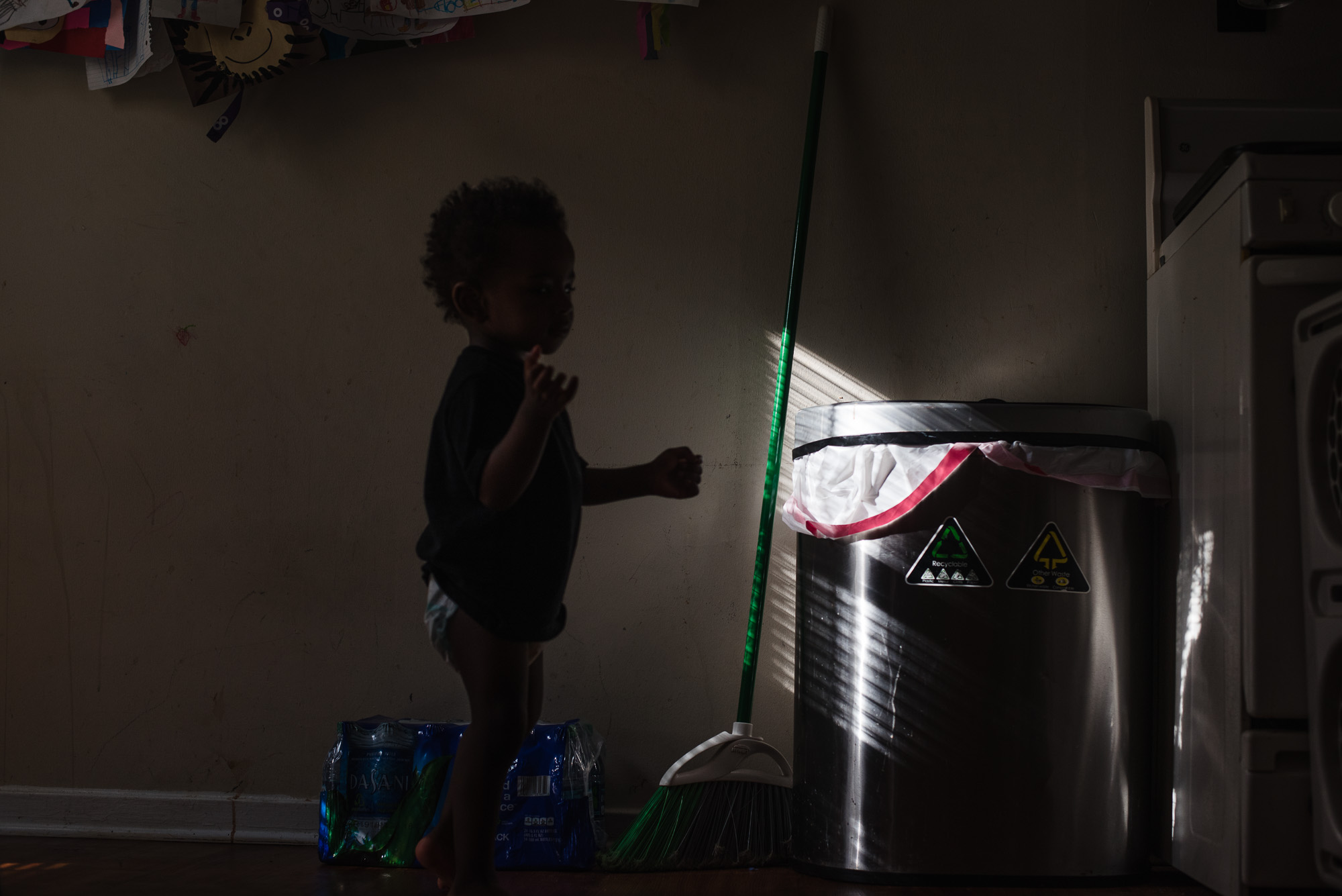 sunlight on trashcan with boy's silhouette - documentary family photography