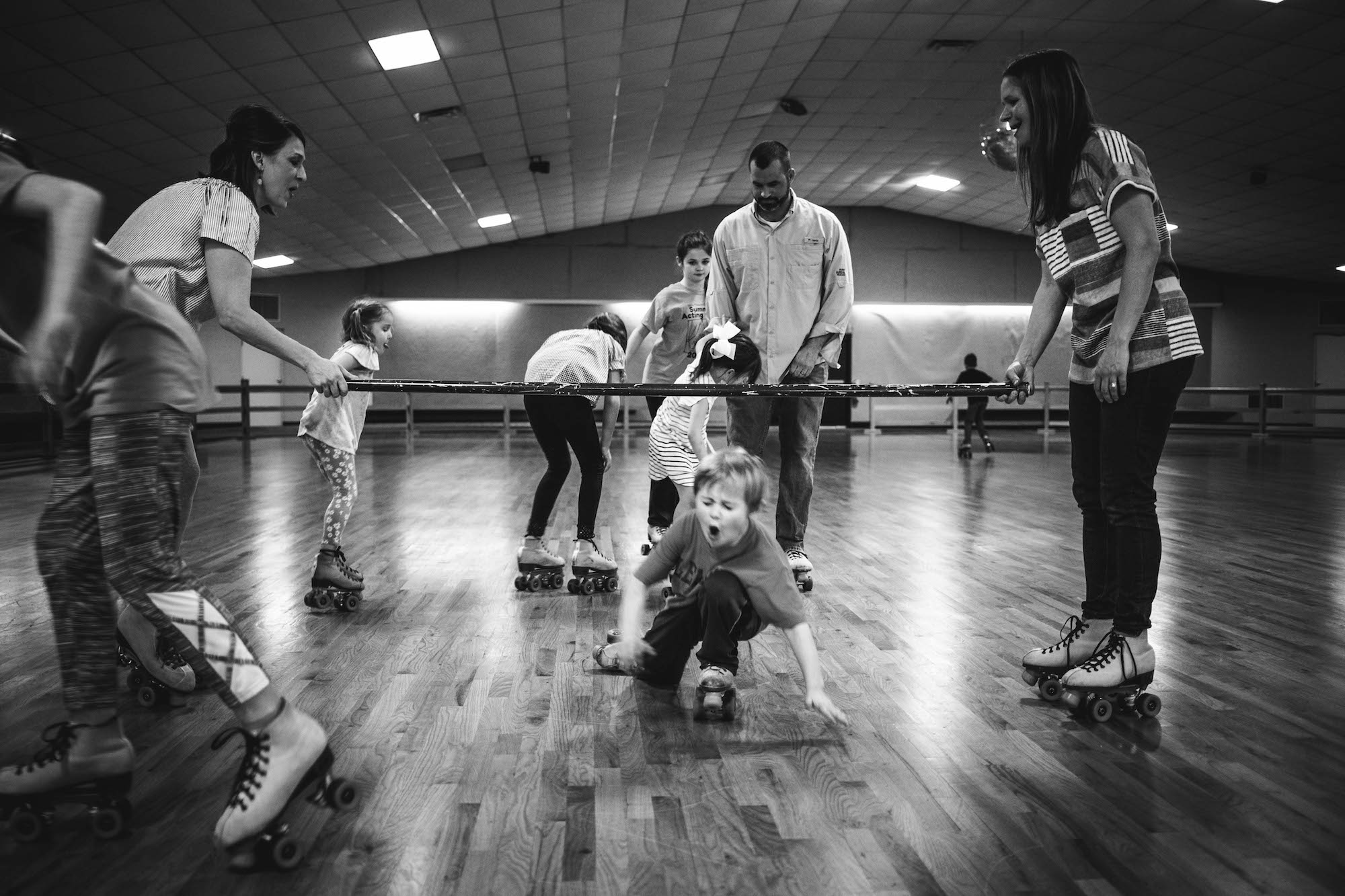 boy falling during roller skate limbo - Documentary Family Photography