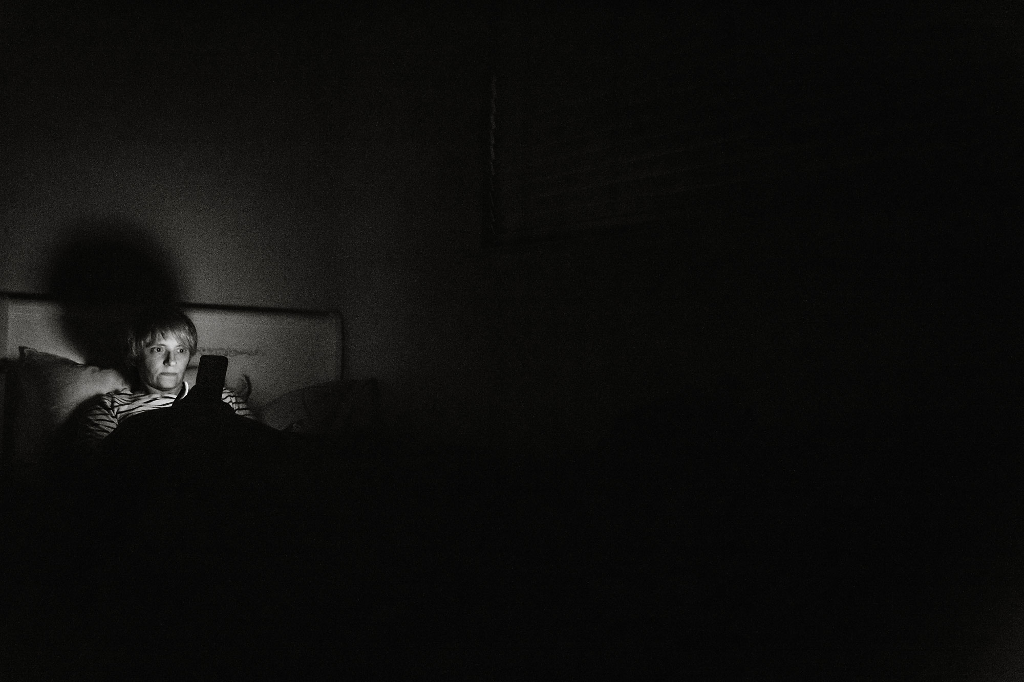 woman with phone in bed -Documentary Family Photography