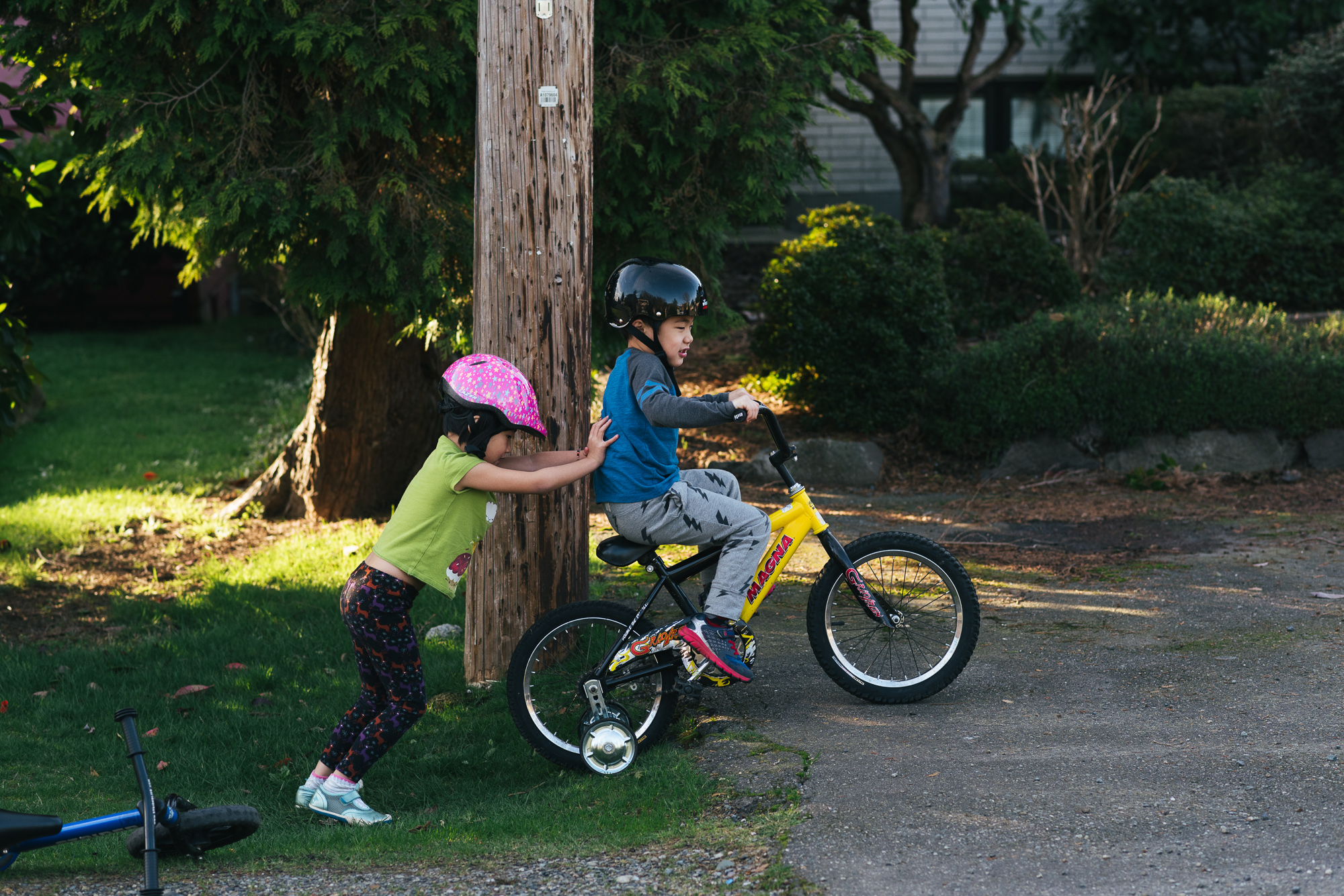 sister pushing brother on bike - Documentary Family Photography