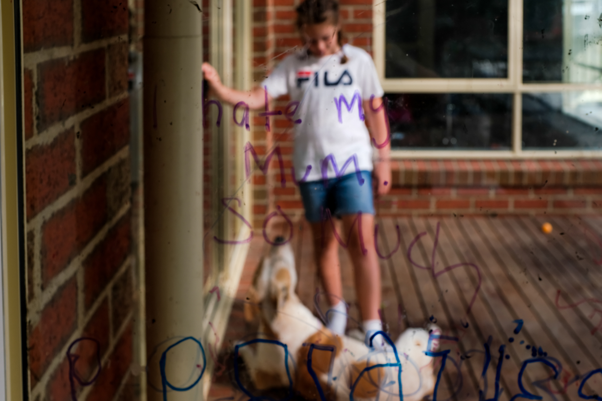 girl with dog through window with marker - documentary family photography