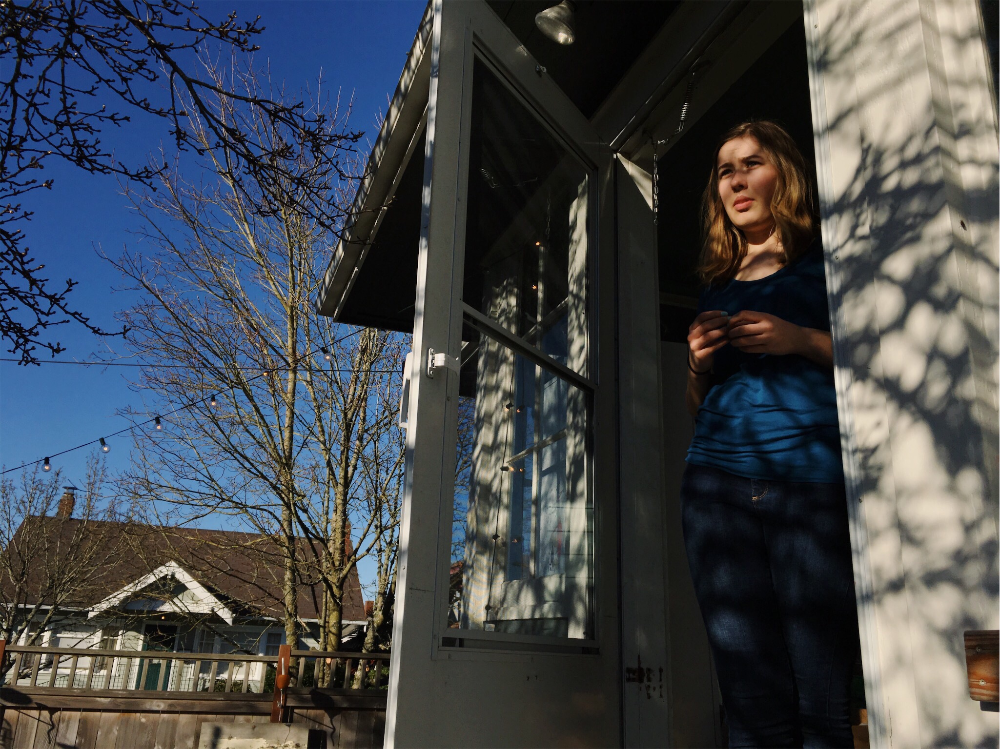 girl at door in dappled light - documentary family photography