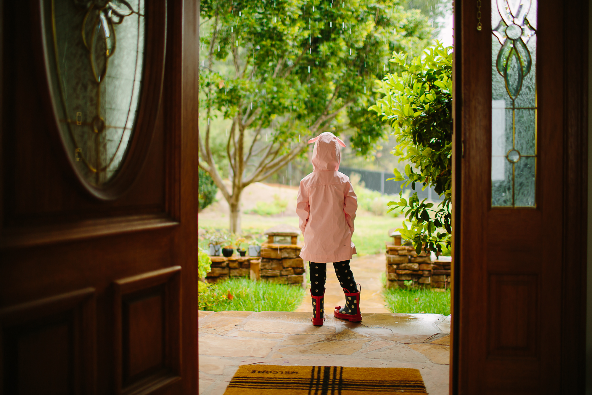 child on porch in raincoat - Documentary Family Photography