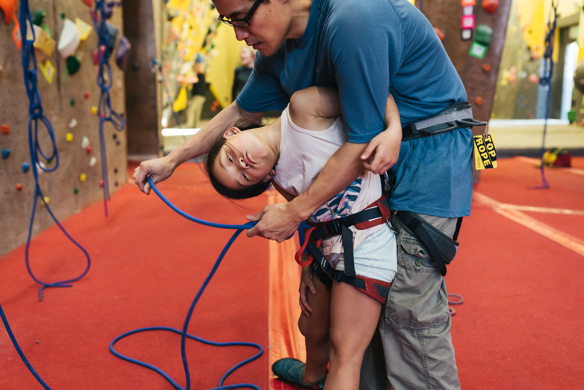 father helping daughter with climbing harness - Documentary Family Photography