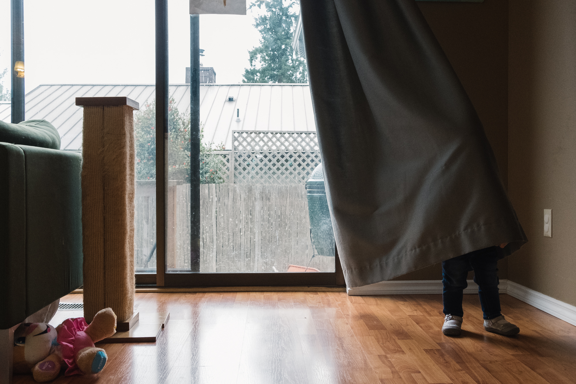 toddler hides in curtains - documentary family photography