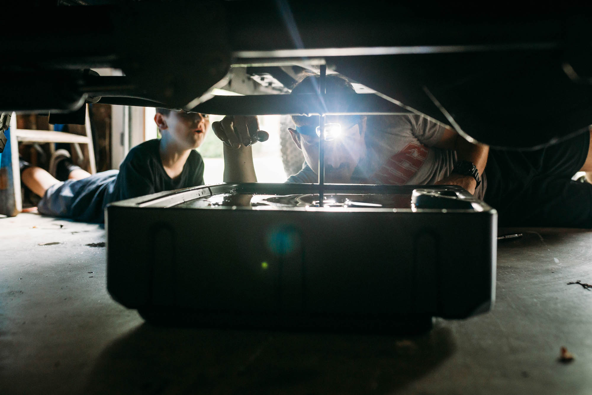 father and son changing oil - documentary family photography