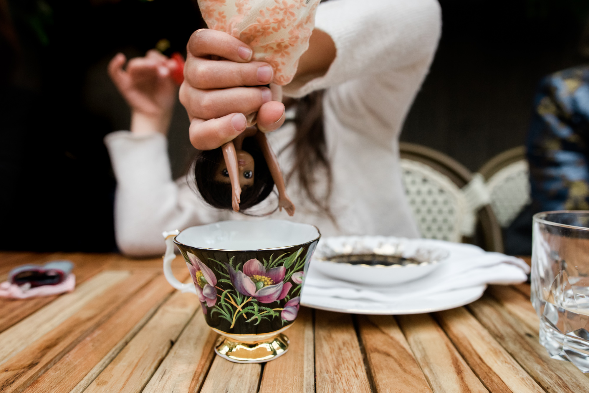 girl dipping doll in teacup - documentary family photography