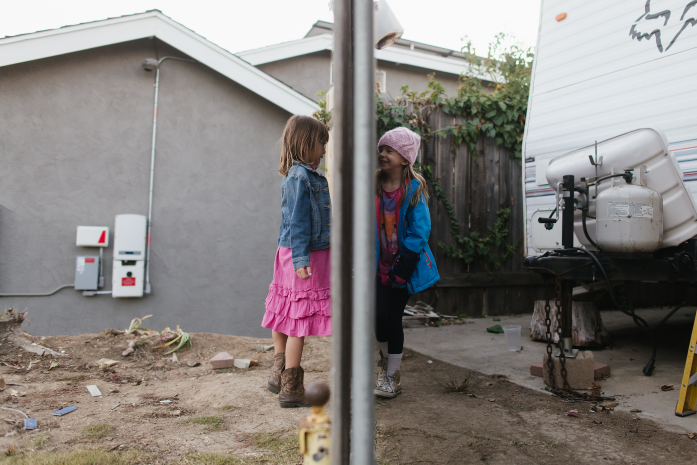 girls on either side of fence - documentary family photography