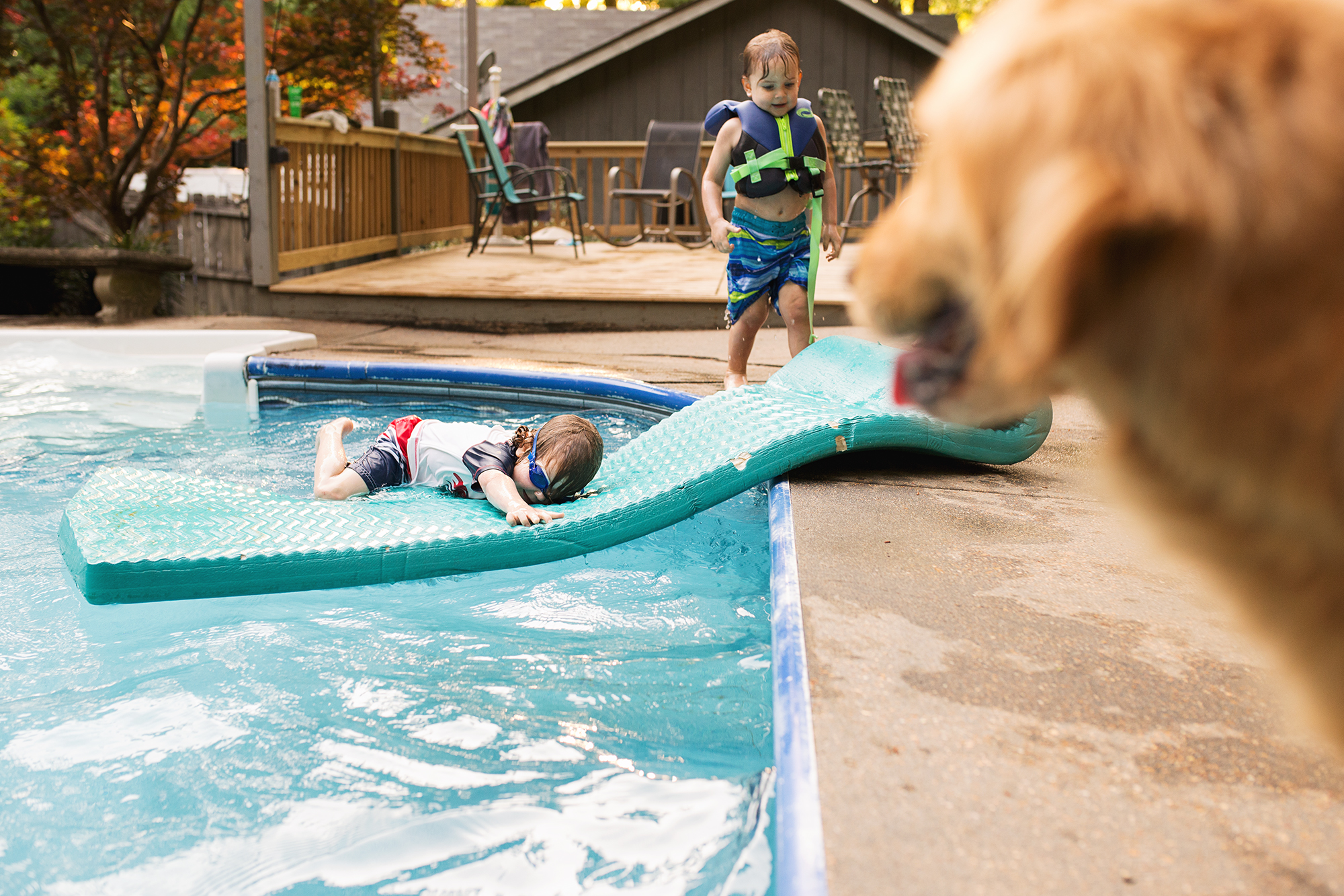 kid sliding into pool on raft - documentary family photography
