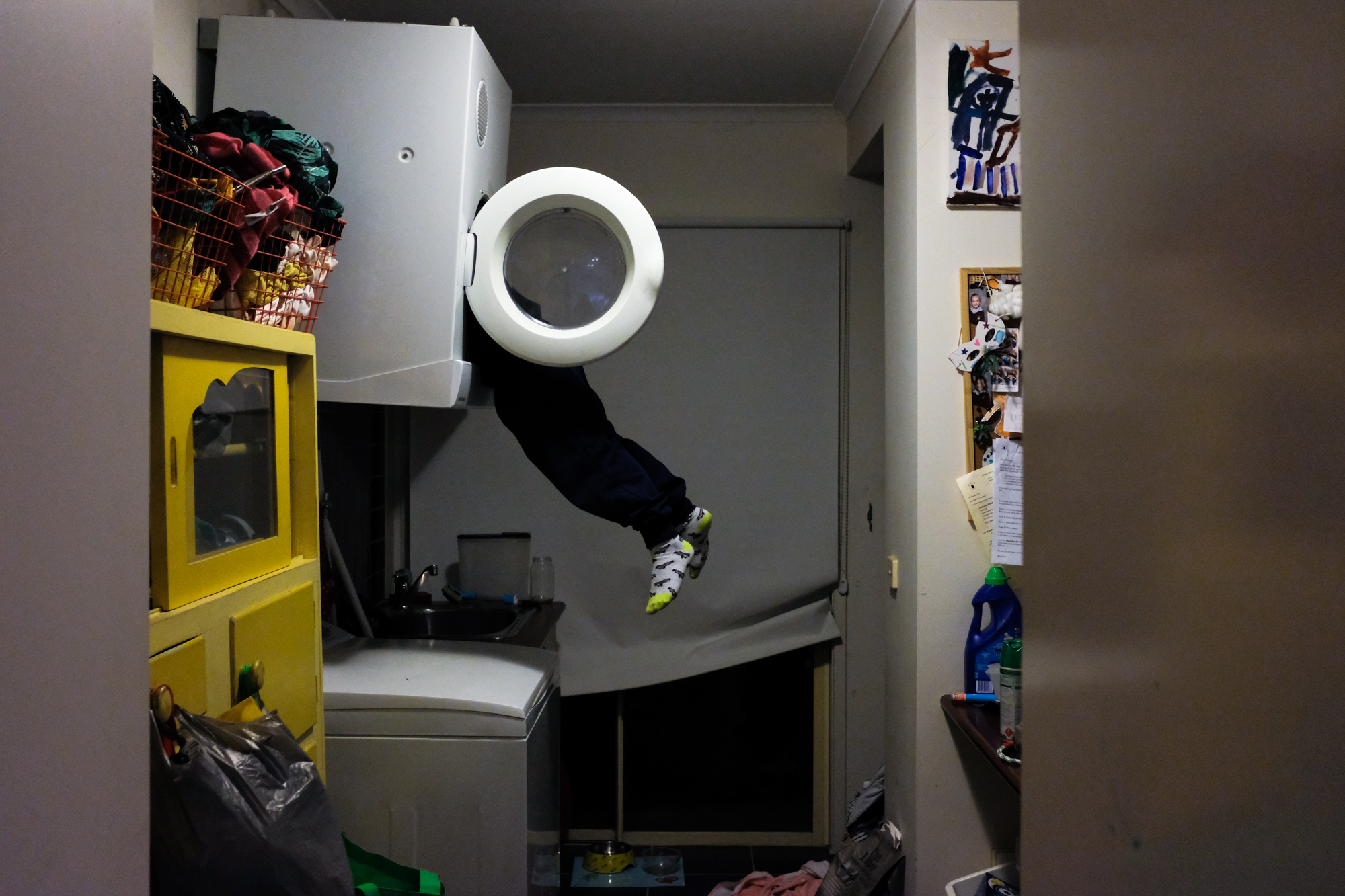 kid hanging out of dryer - documentary family photography