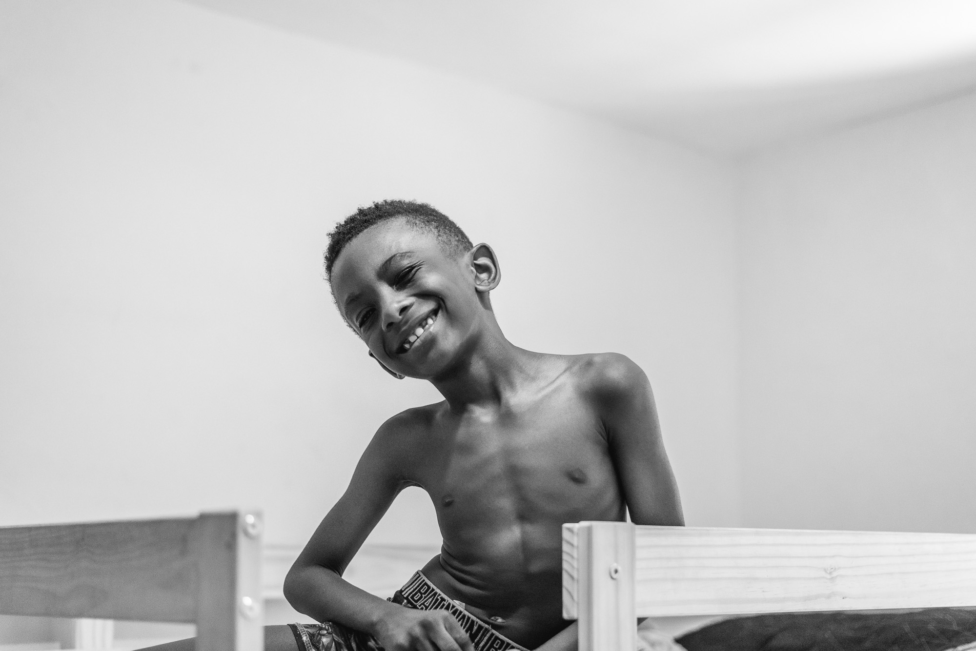 boy in bed grinning - Documentary Family Photography