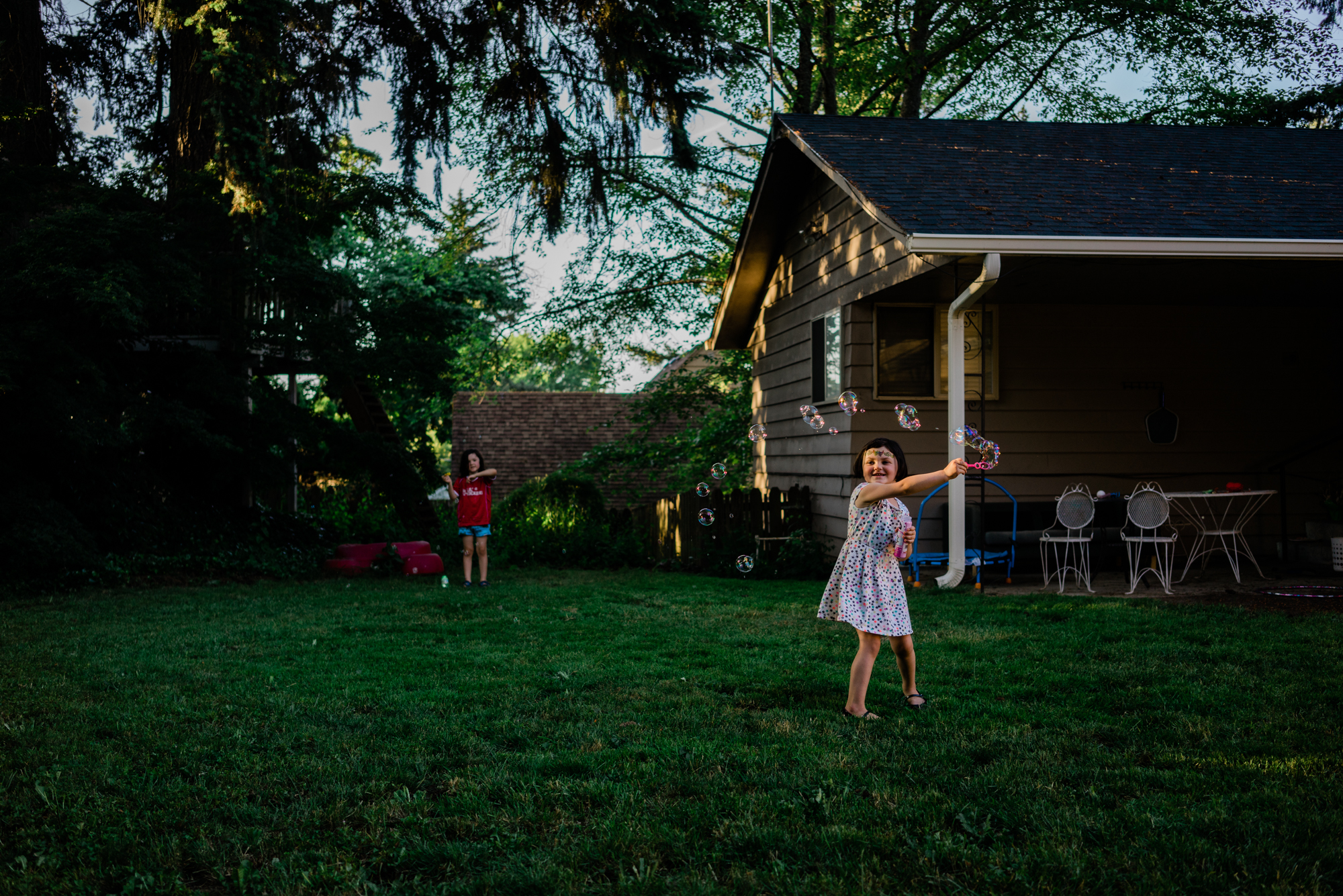 girl blowing bubbles in back yard - documentary family photography