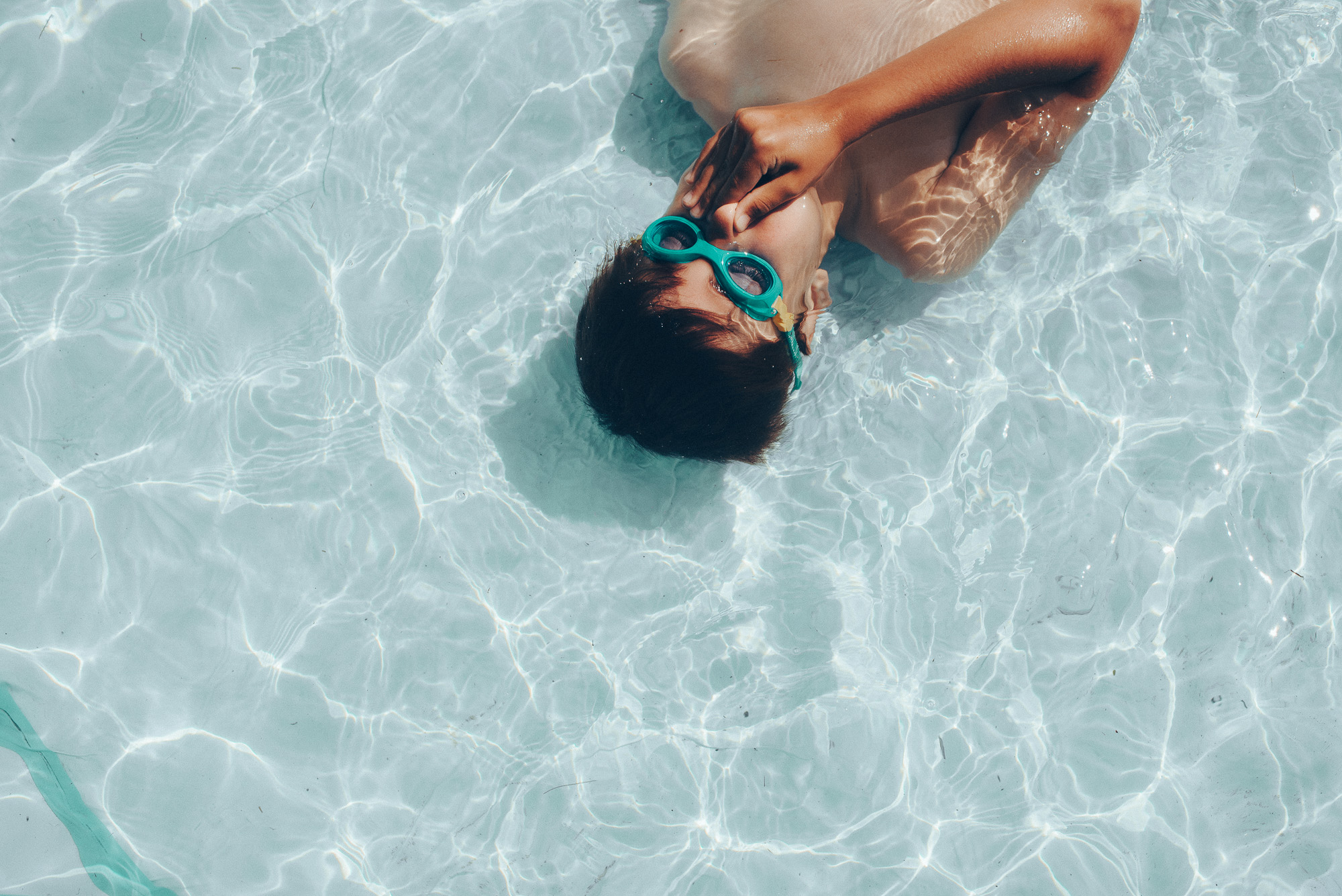 boy in pool plugging nose - documentary family photography